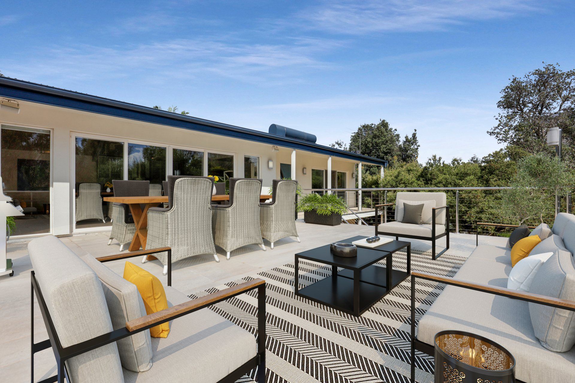 Outdoor patio with cushioned seating, coffee tables, and a stone fireplace beside a modern house.