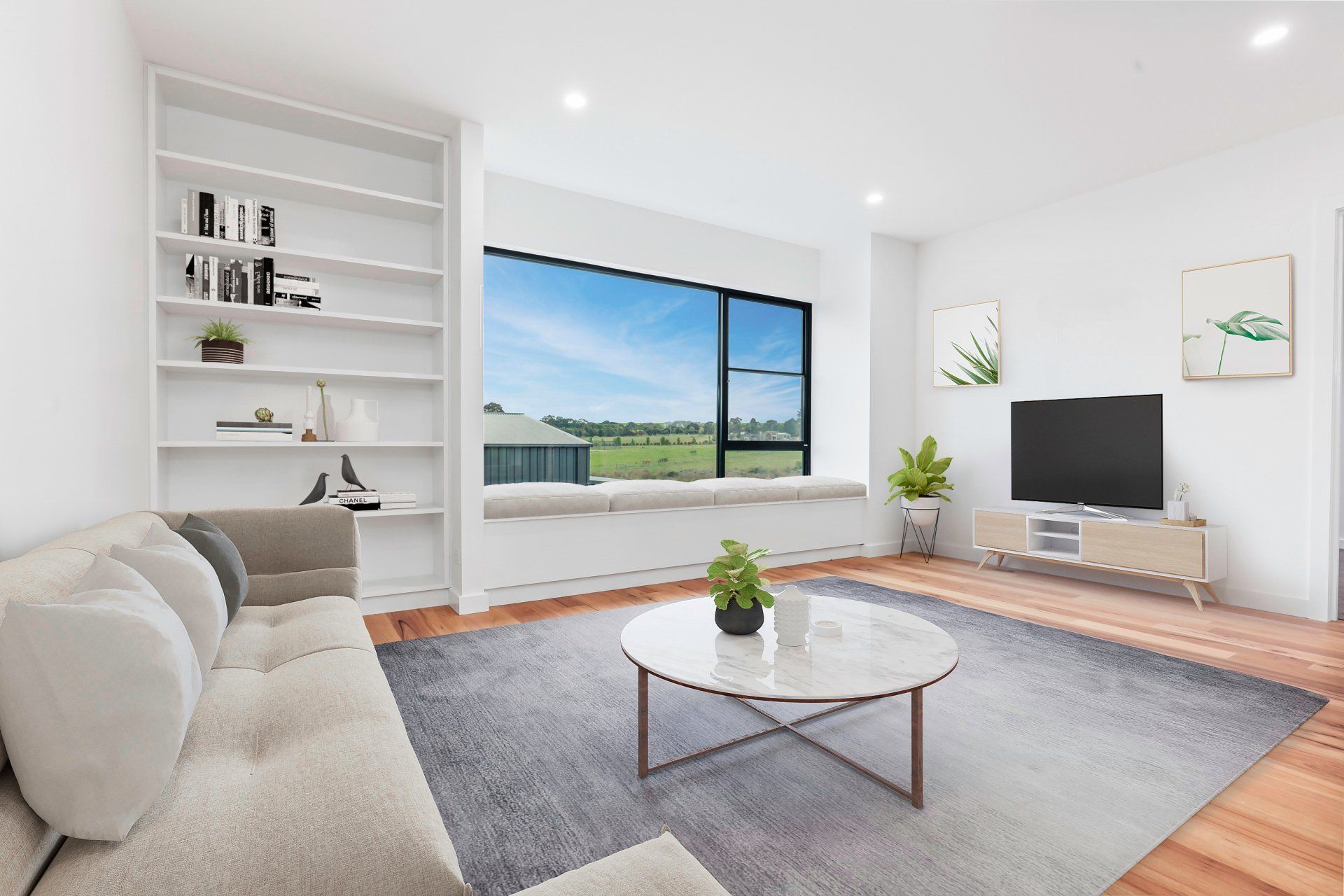 Bright modern living room with white sofa, large window, TV, and a round coffee table on a rug