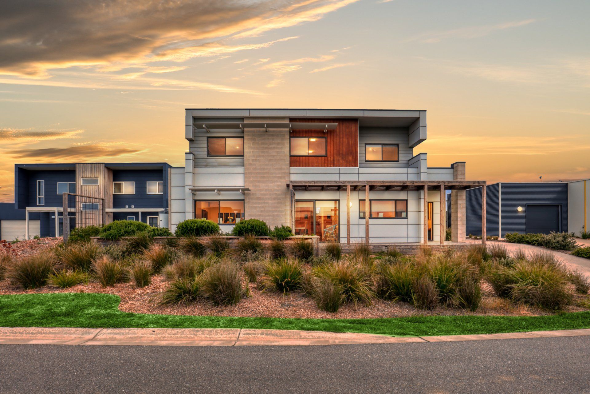 Modern two-story house with large windows and desert landscaping at sunset