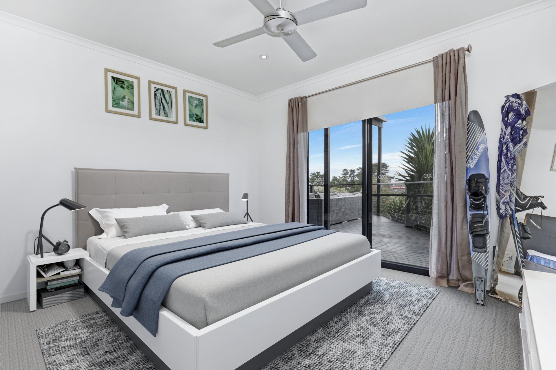 Modern bedroom with gray bed, blue bedding, wall art, and sliding doors to a balcony.