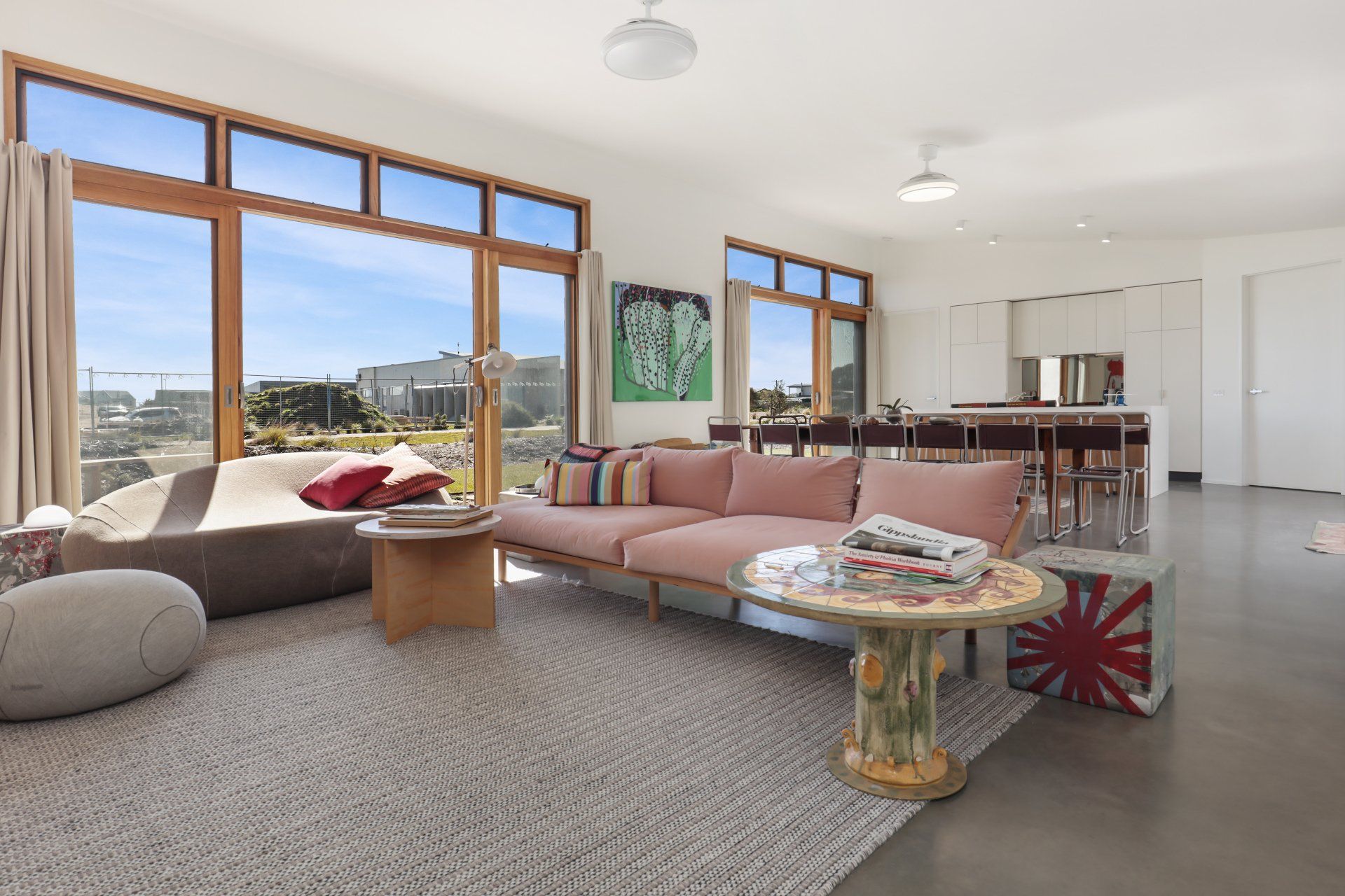 Bright living room with large windows, pink sofa, beige rug, and mountain view