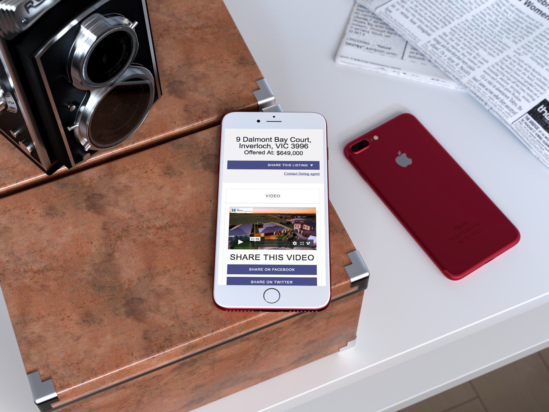 Two smartphones on a white surface beside a vintage camera and newspaper, one displaying a web page.