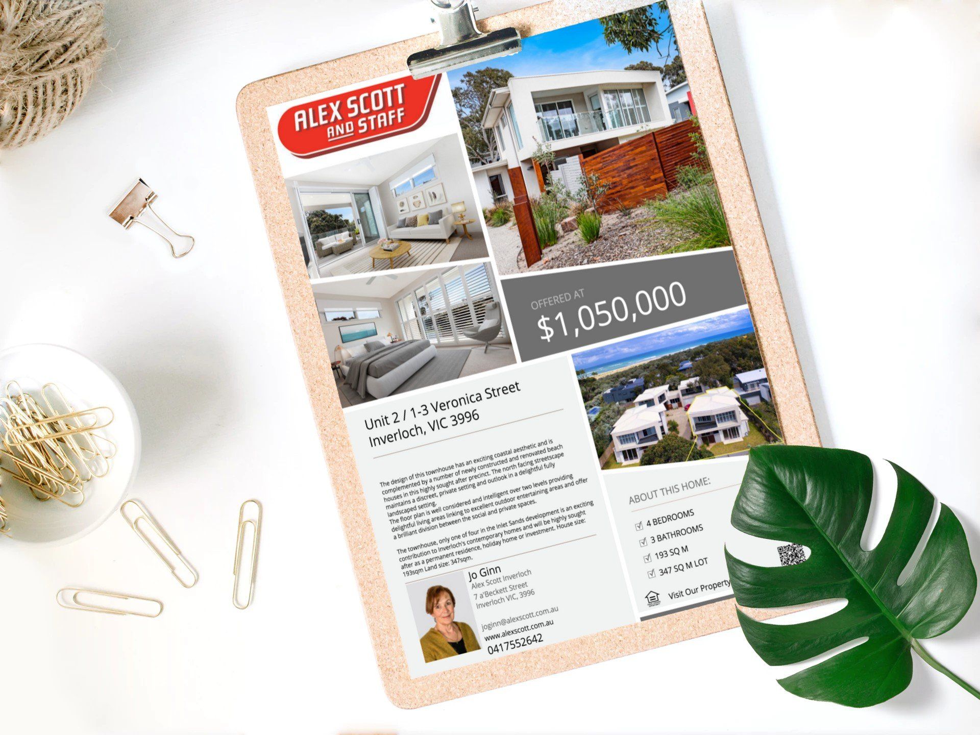 Real estate flyer with house photos, $1,050,000 price, clipboard, and green leaf on white desk