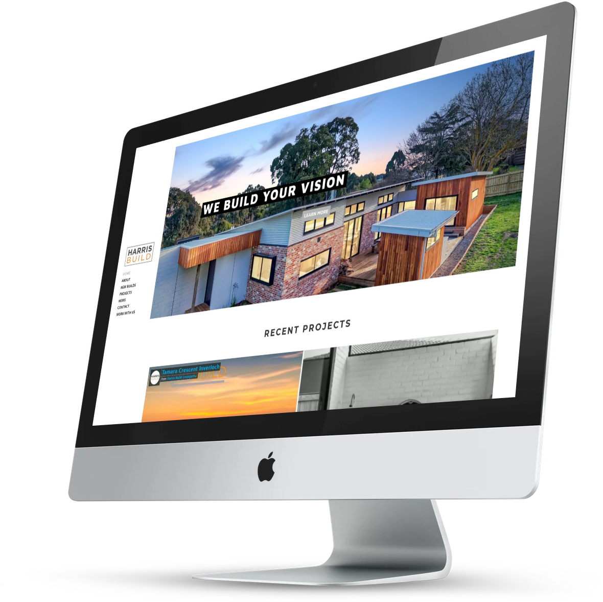 Silver iMac displaying a website with a modern house and the headline “WE BUILD YOUR VISION”