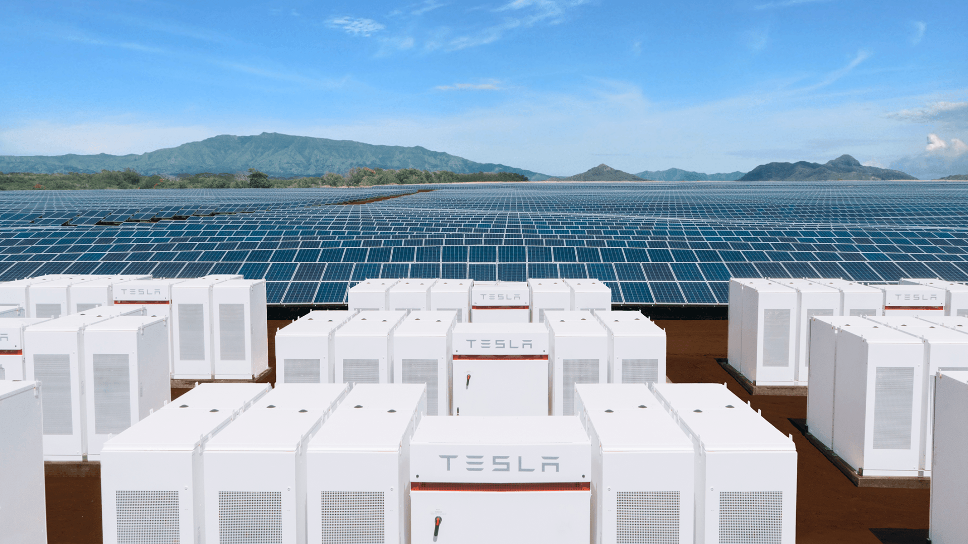 Tesla battery storage facility with solar panels and a mountain backdrop.