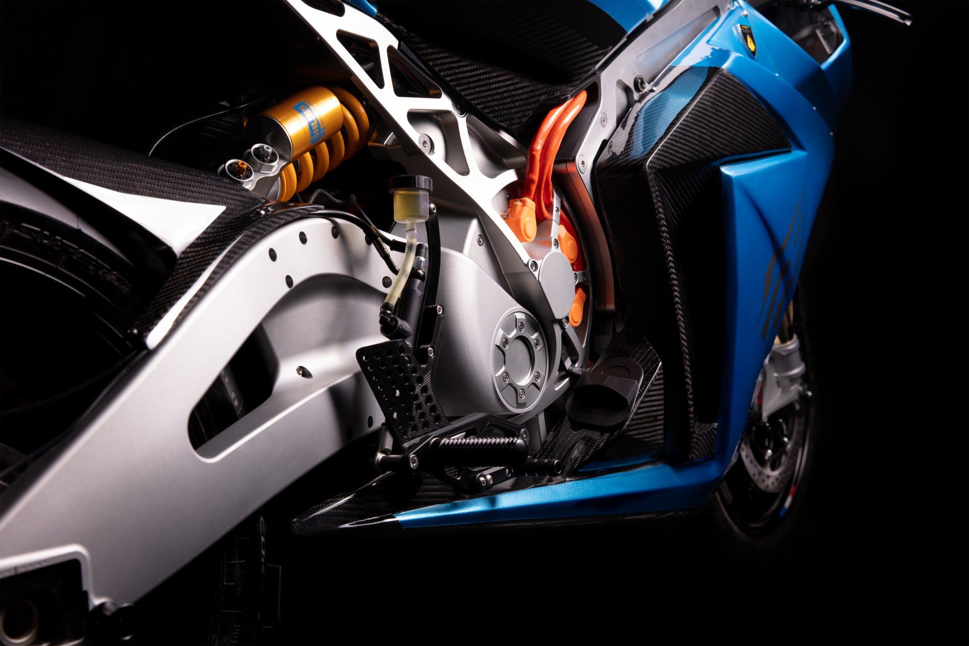 Blue electric motorcycle, silver frame, gold suspension, dark background.