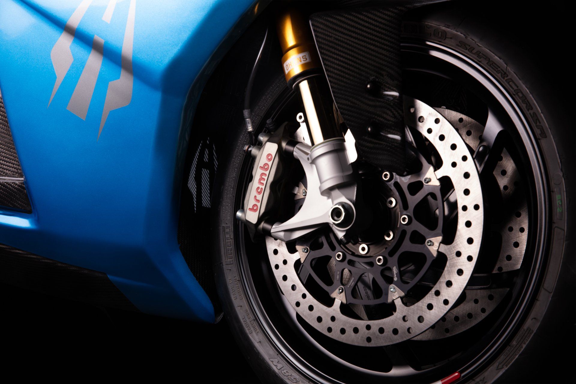 Blue motorcycle front wheel with a Brembo brake caliper and drilled rotors.
