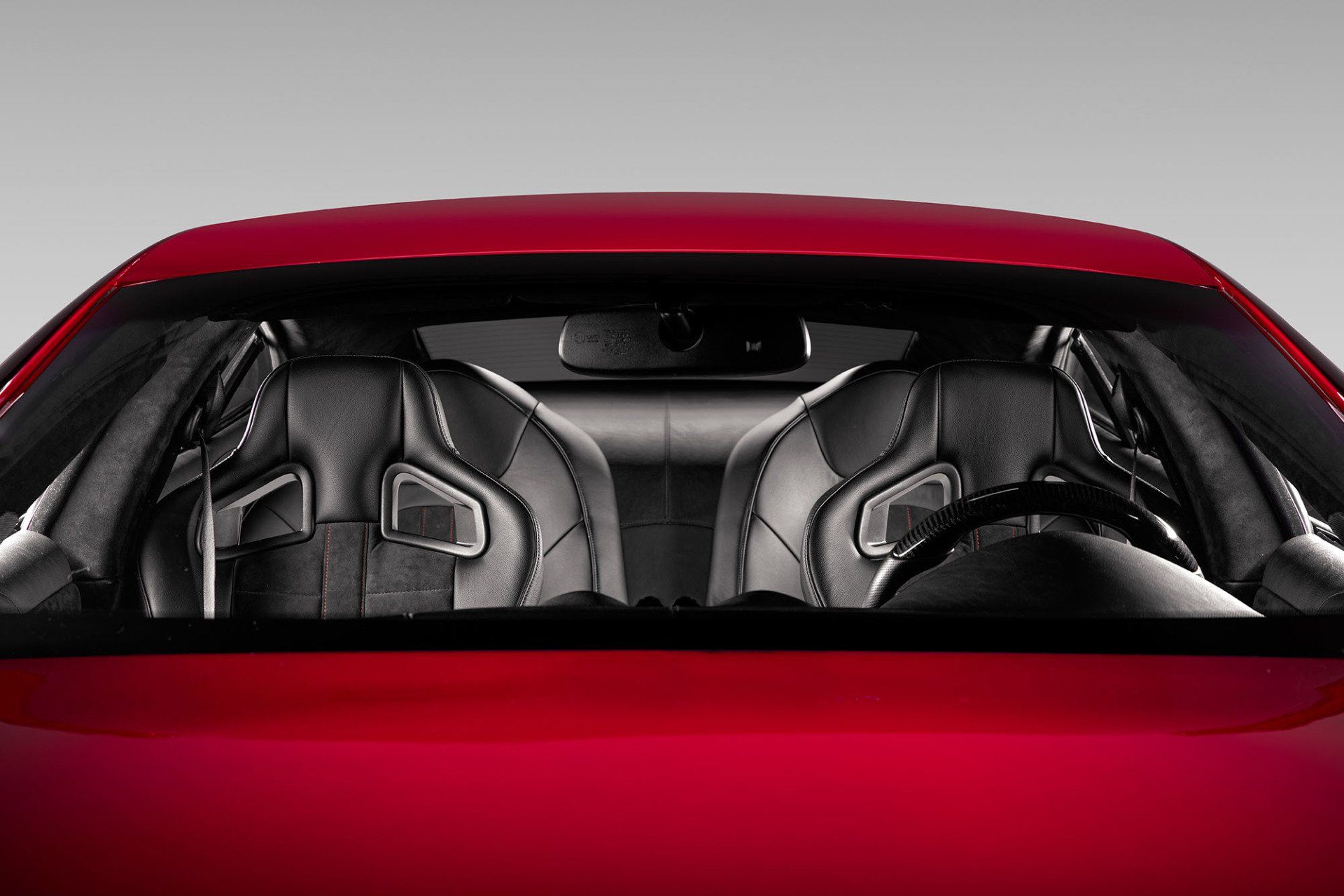 Red car interior, black bucket seats, steering wheel visible.