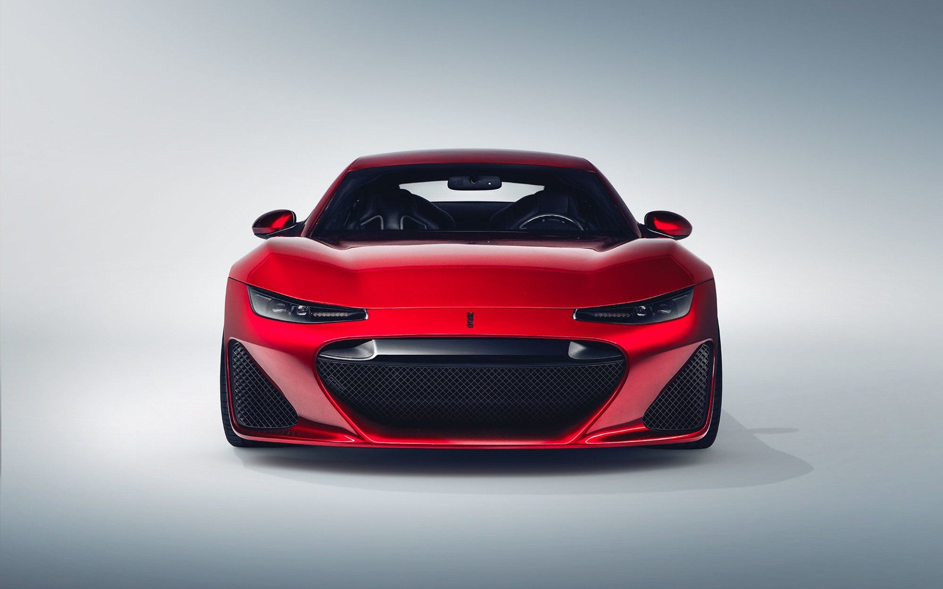 Red sports car, front view, black grill, on a light gray background.