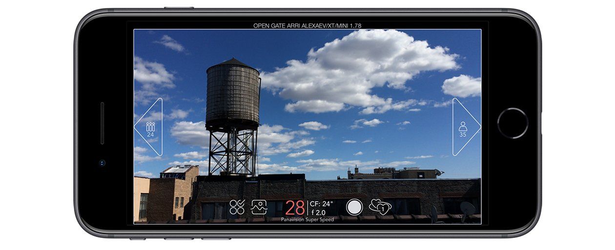 A smartphone camera displays a rooftop with a water tower against a blue sky with fluffy clouds.