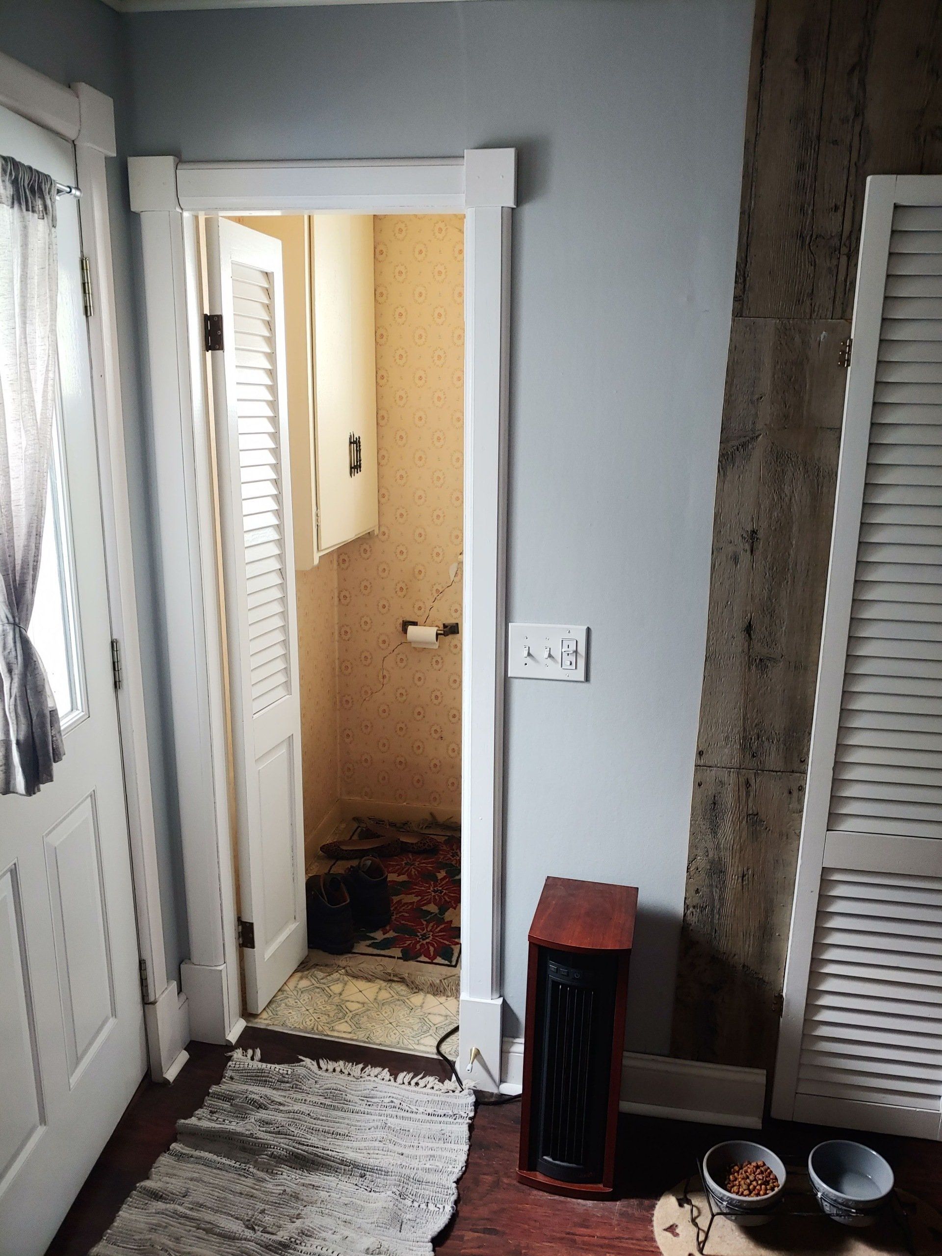 Narrow hallway with open door, gray walls, patterned floor runner, and a small heater near the entrance