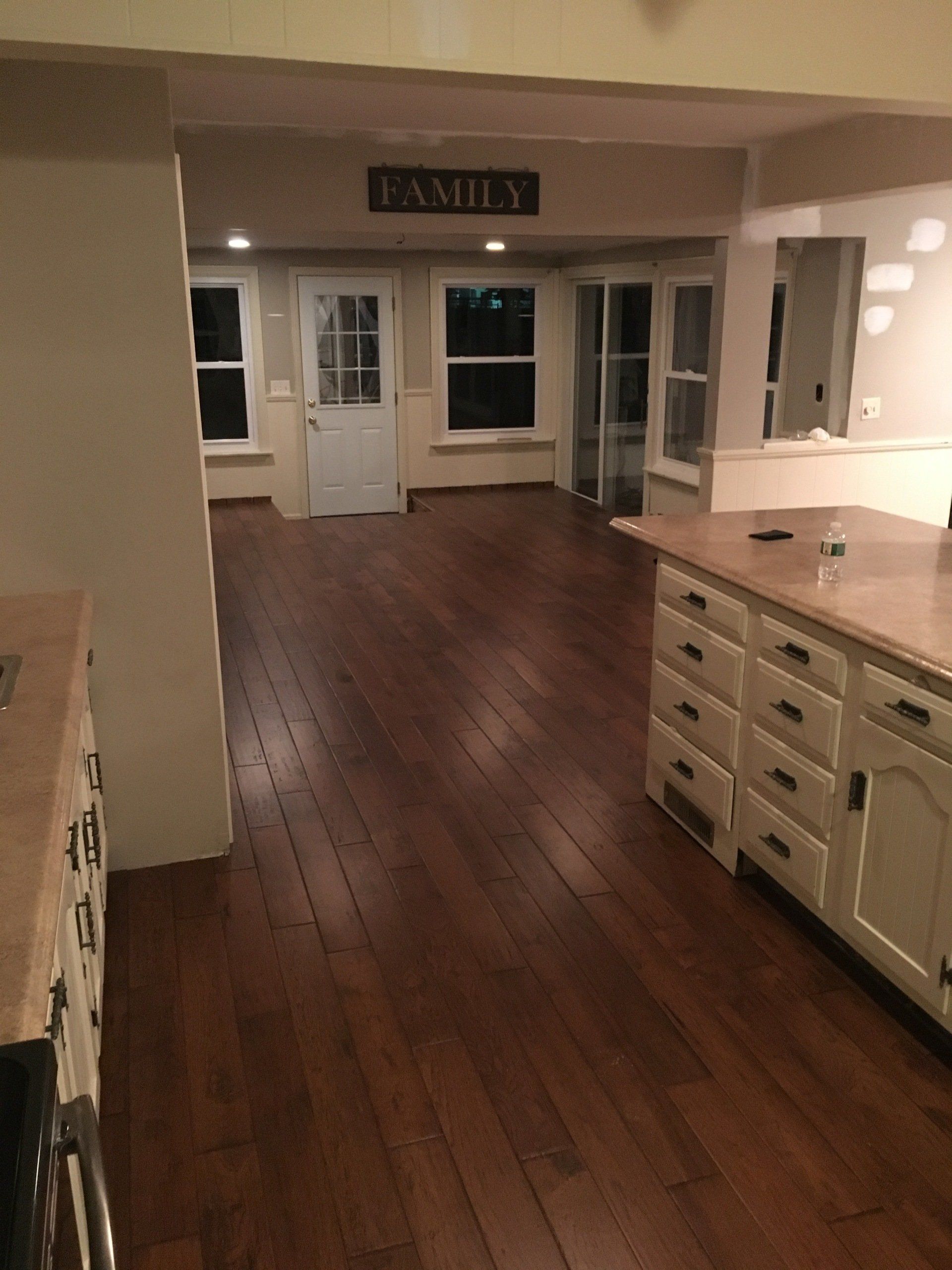 Empty kitchen with dark wood floors, white cabinets, and glass doors leading to a patio.