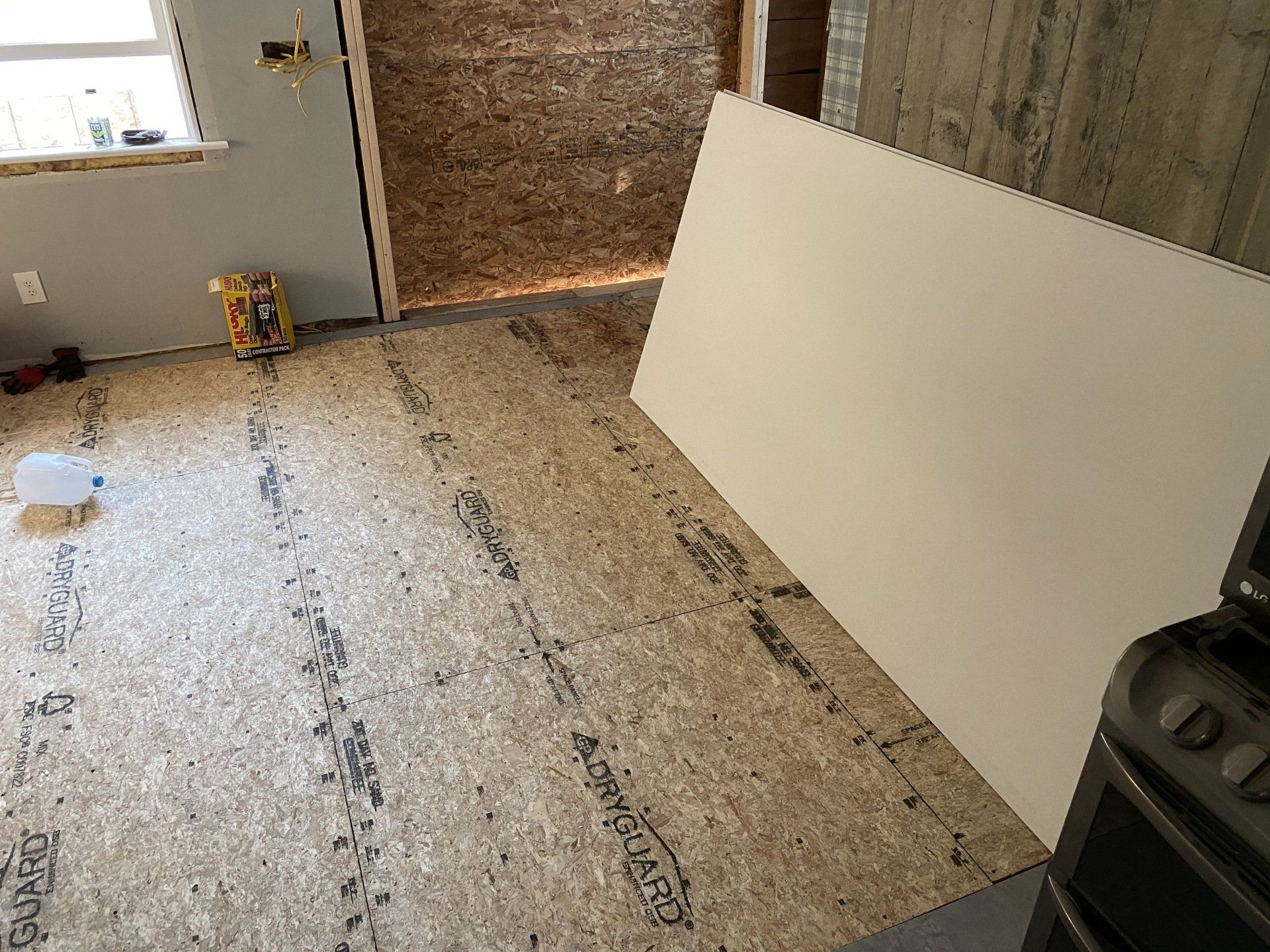 Partially finished room with insulation, subflooring, and a large white panel leaning against the wall