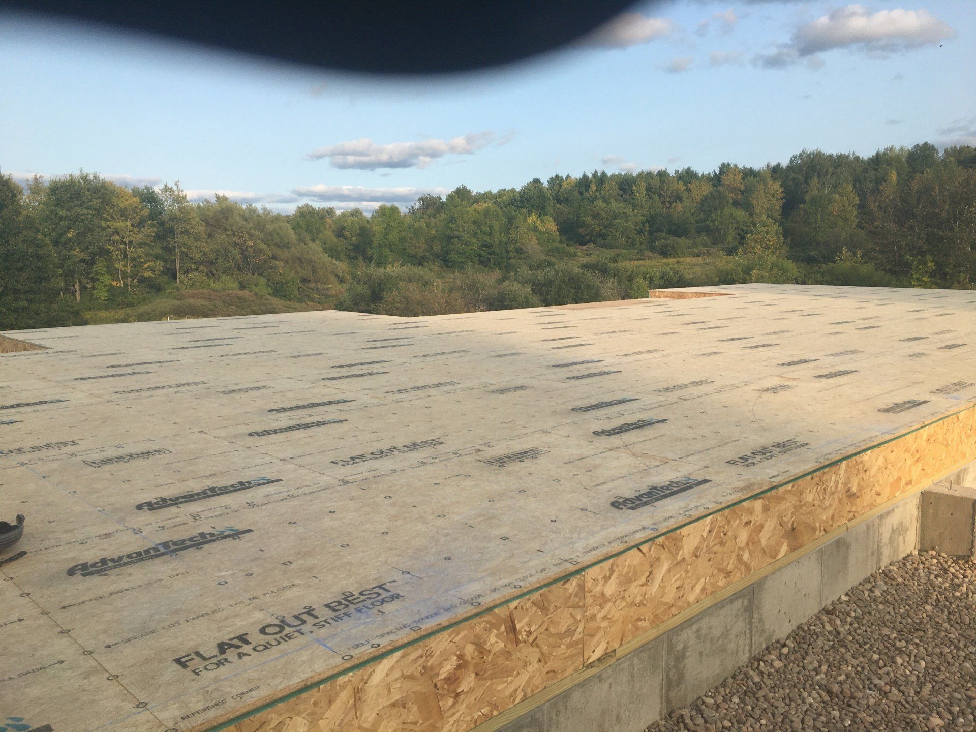 Flat rooftop with underlayment and forested landscape in the background