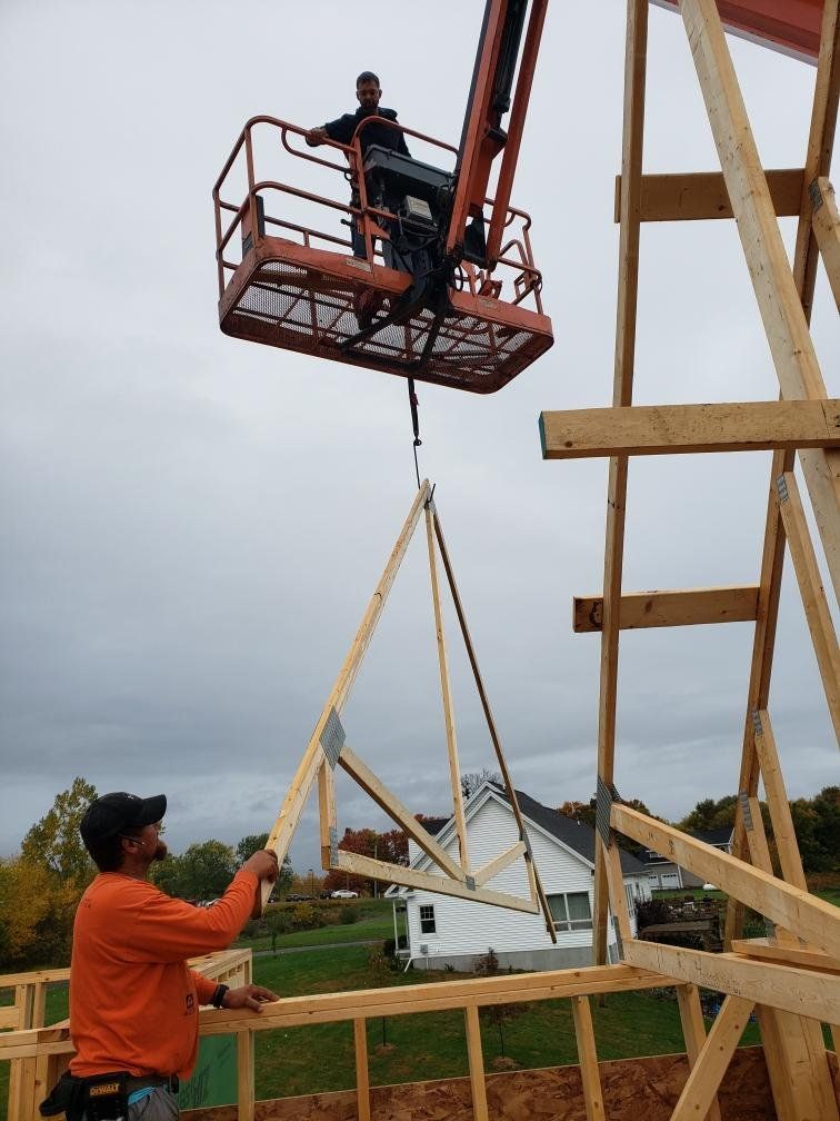 Two workers guiding a large beam into place on a wooden frame at a construction site.