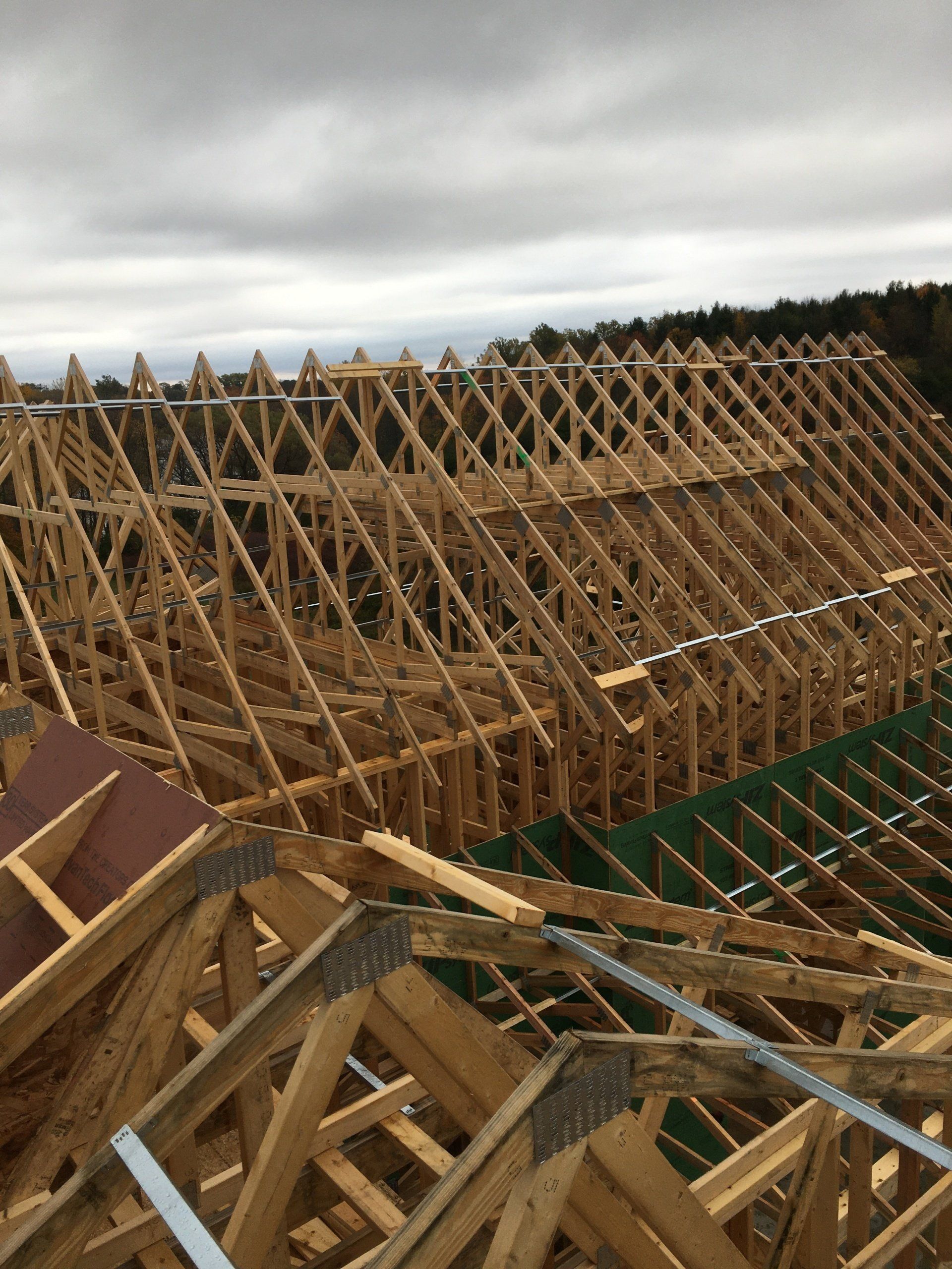 Wooden roof trusses under construction against a cloudy sky