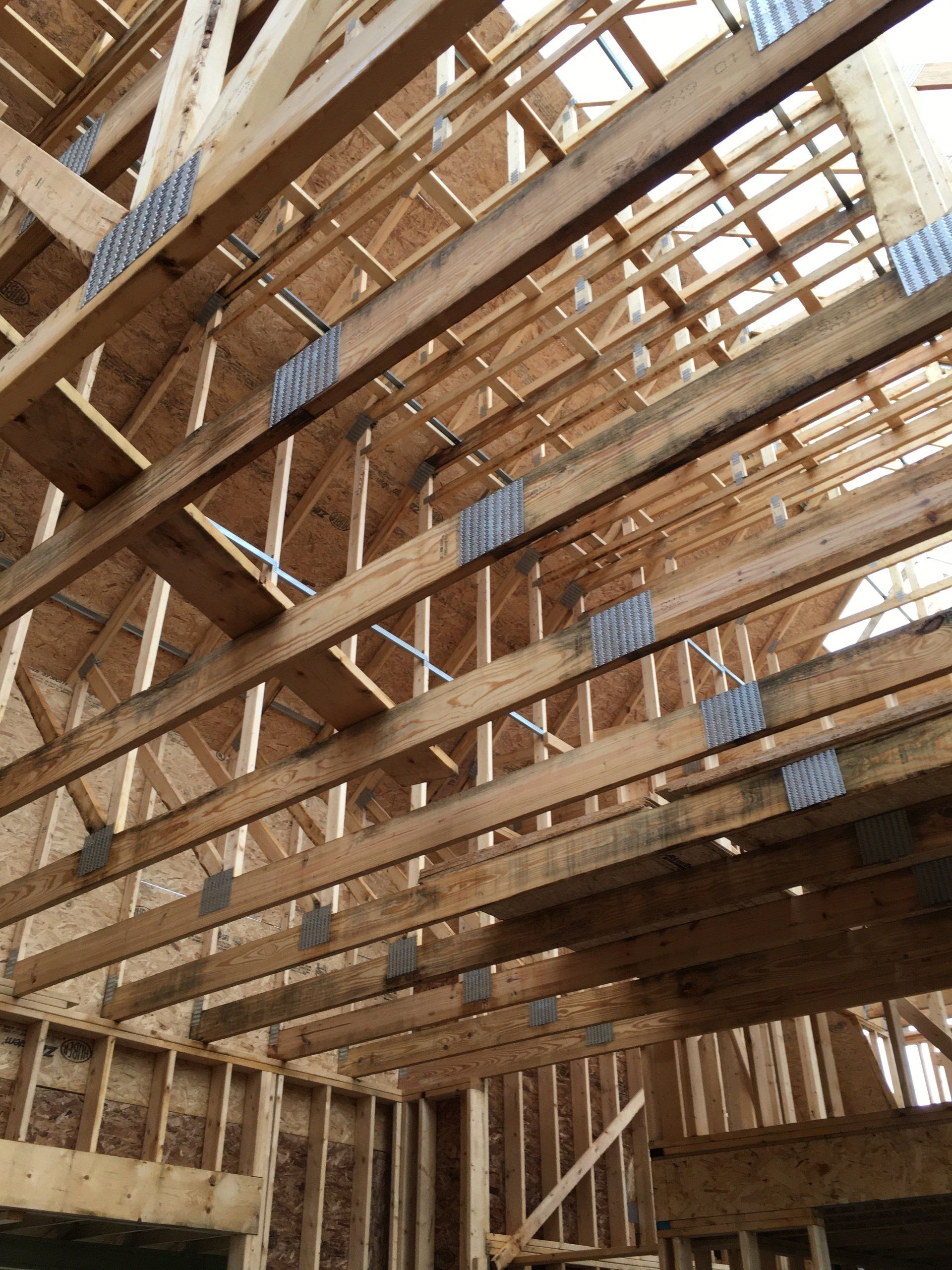 Interior of a wood-framed building under construction, showing exposed beams and roof trusses.