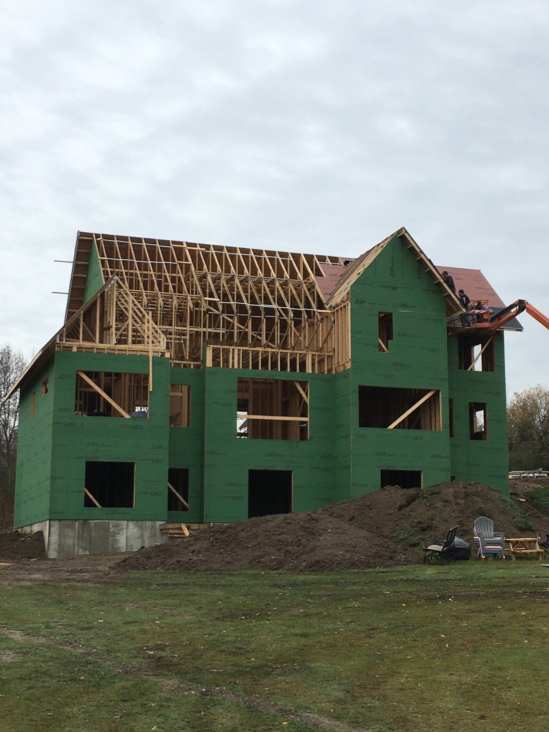 Green house under construction with exposed roof framing and unfinished windows