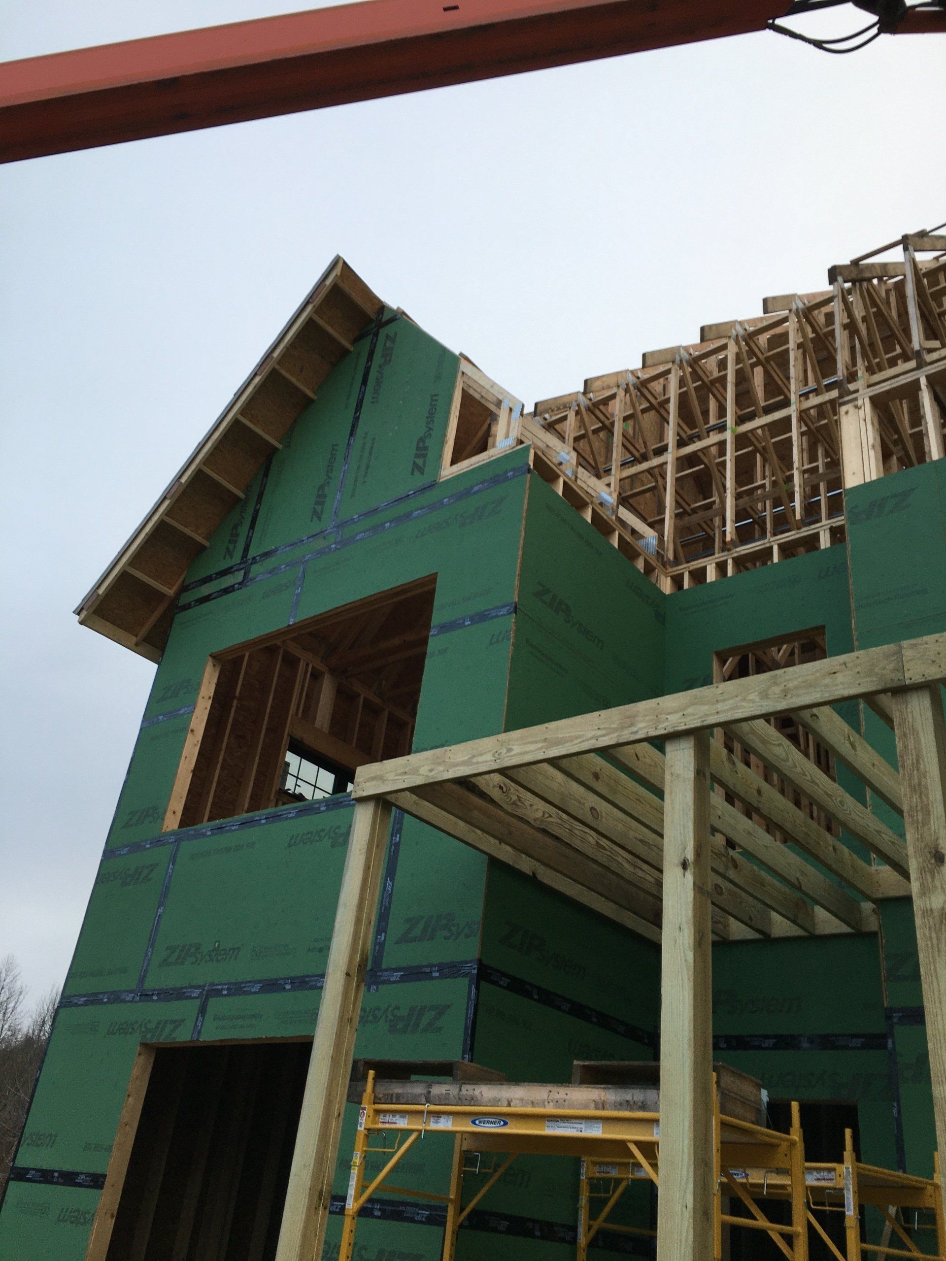 Partially built green house with exposed framing and scaffolding under construction