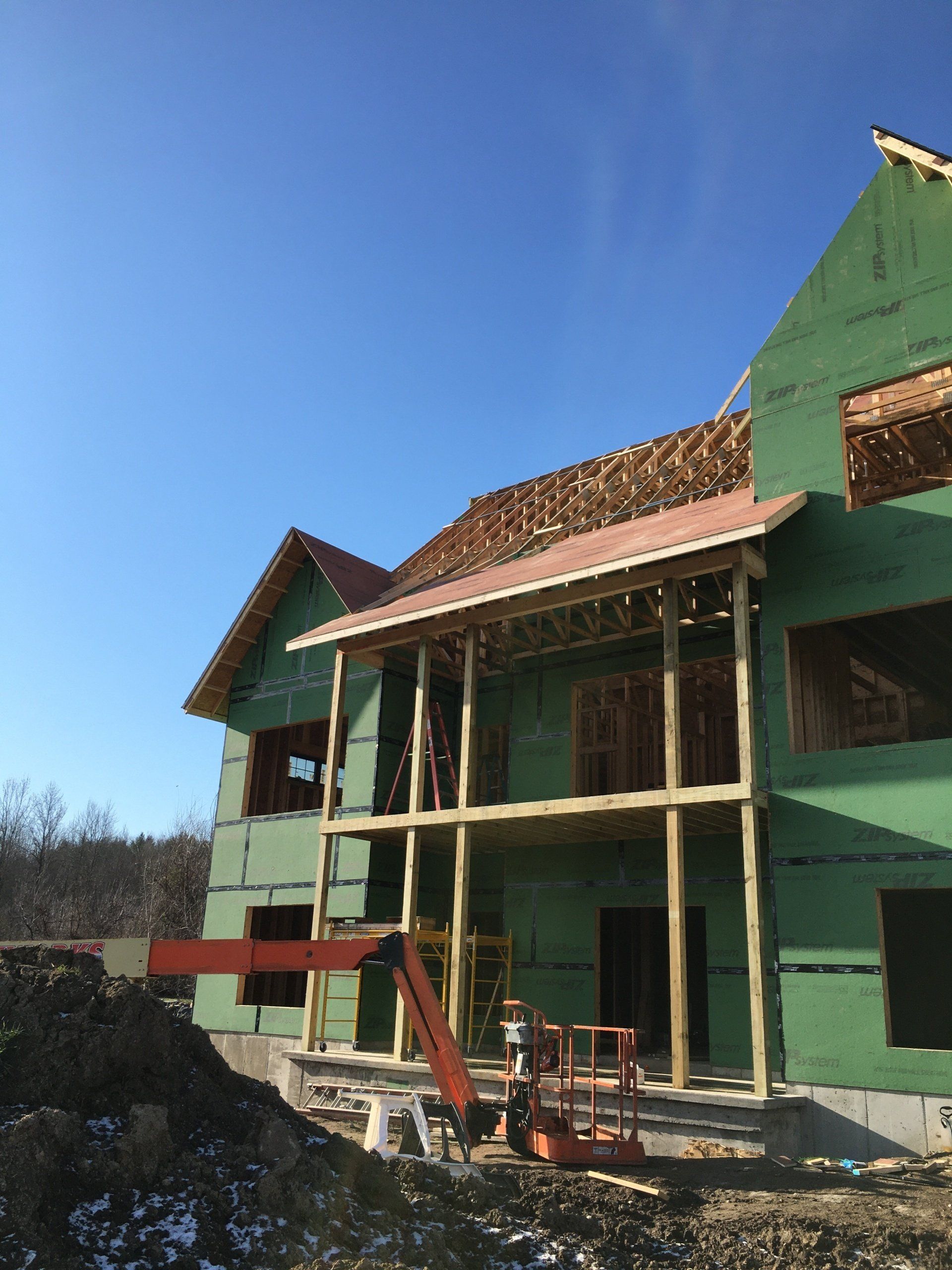 Partially built green house with exposed framing and roof under a clear blue sky