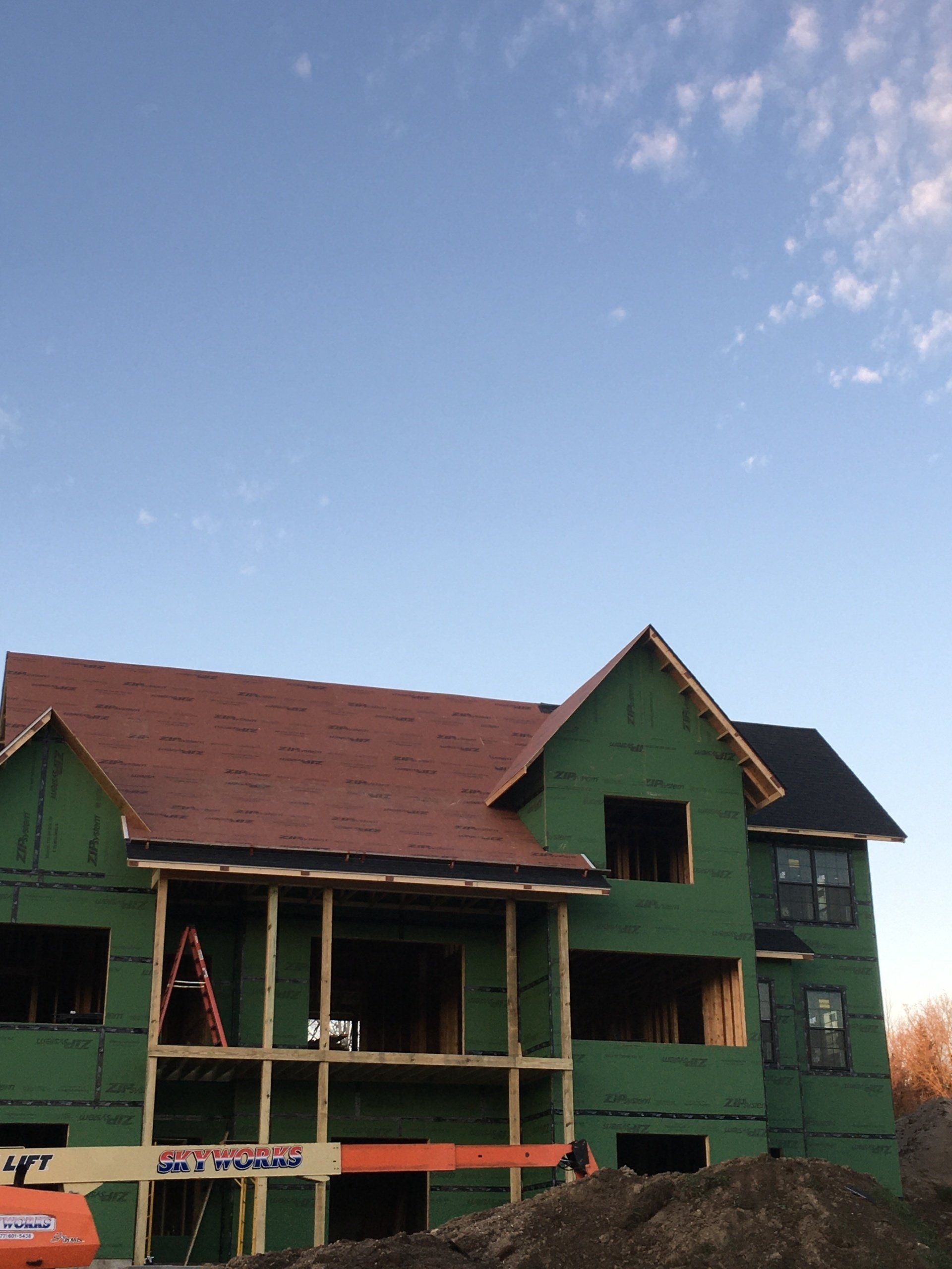 Green multi-story house with red roof under a clear blue sky