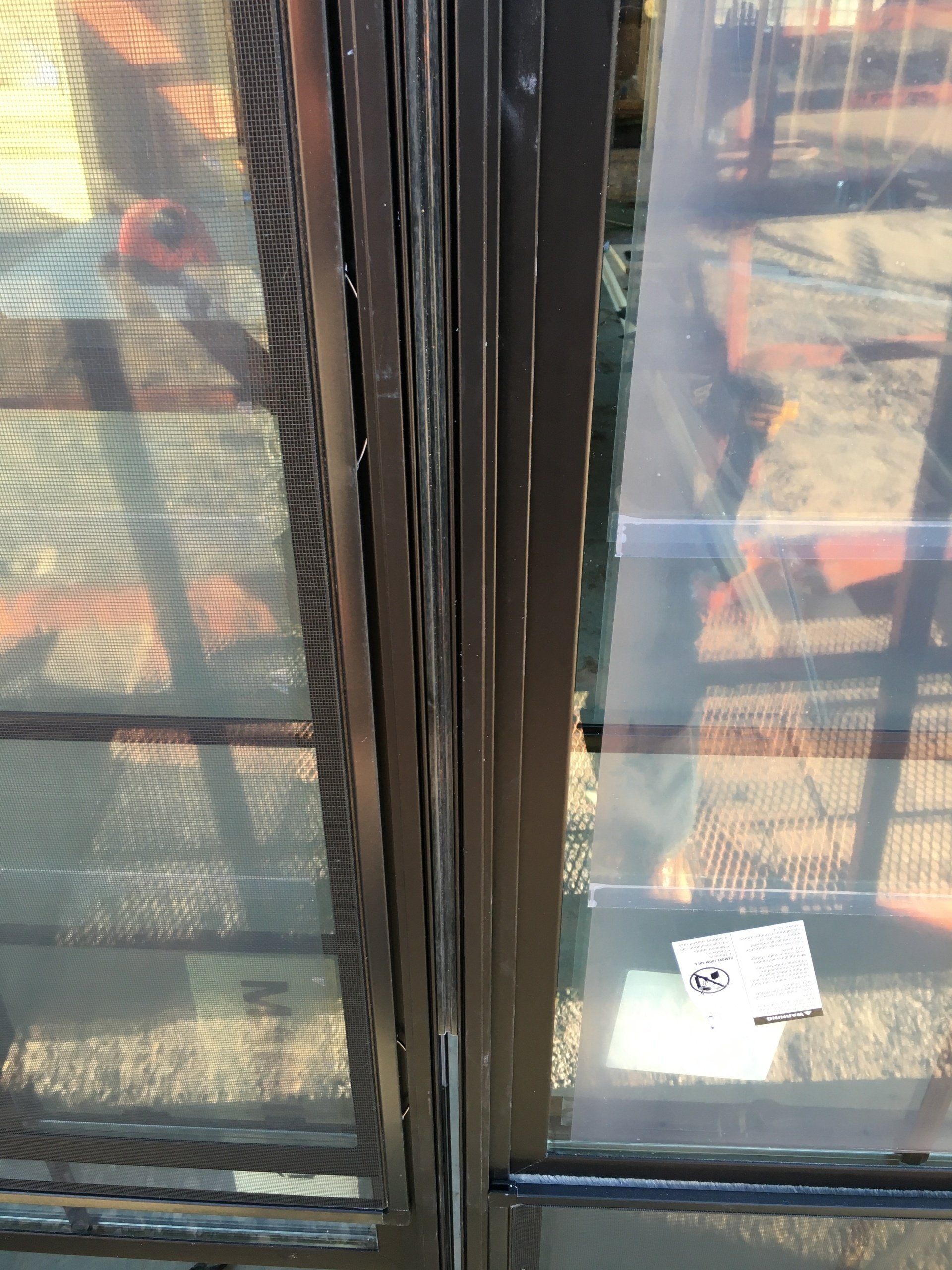 Closed dark-framed glass door with reflections, a small white note taped on the right pane