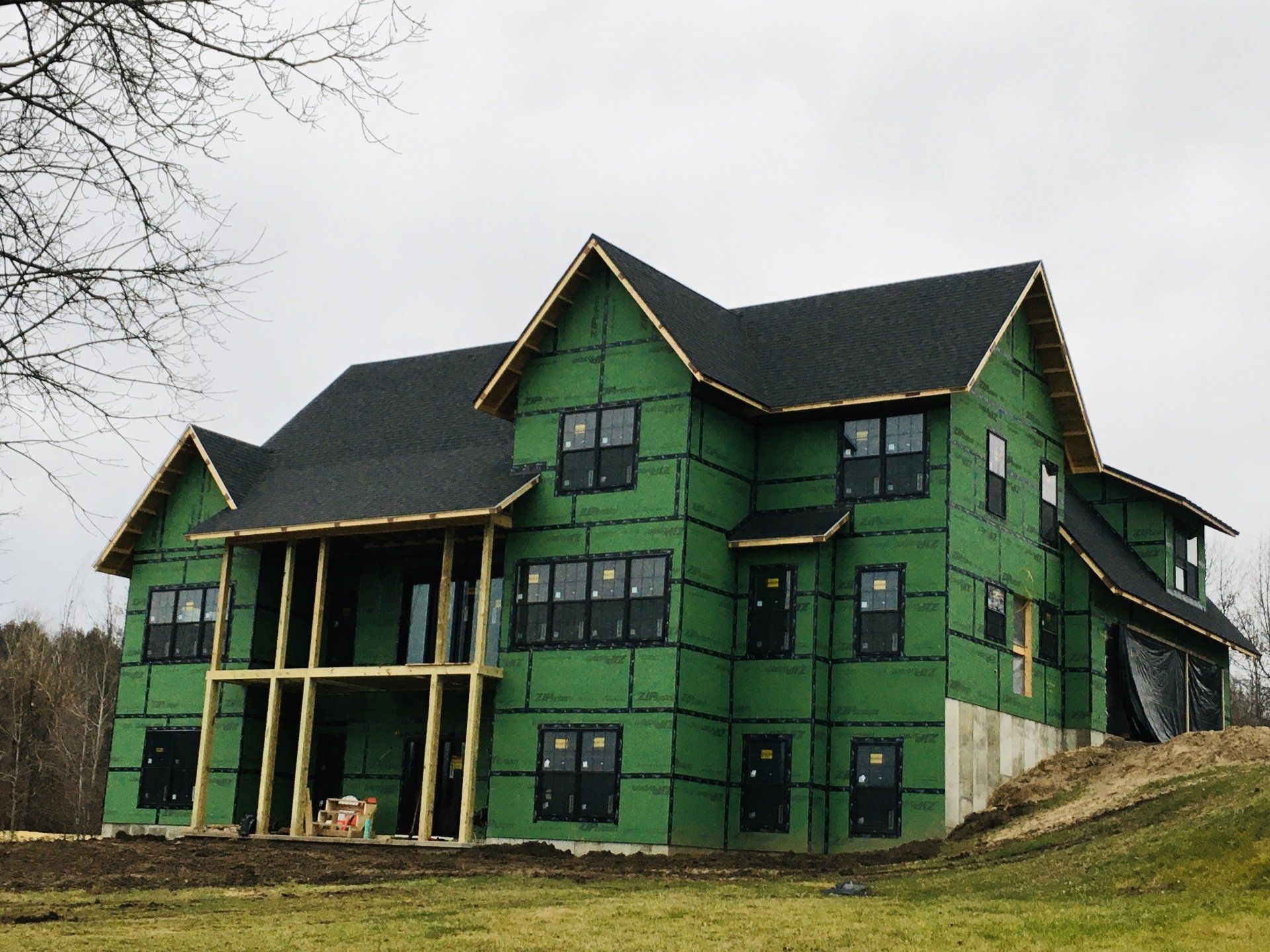 Partially built green house with black roof and exposed framing on a grassy lot