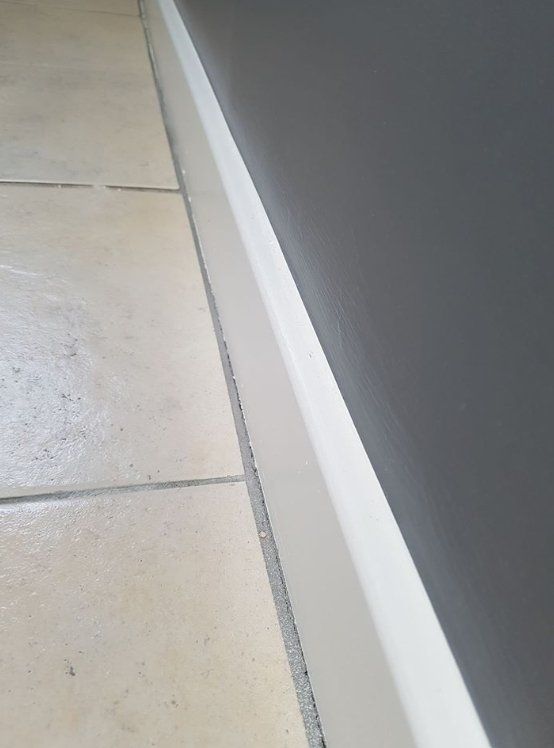 Dark grey painted wall with white skirting and tiled floor in York
