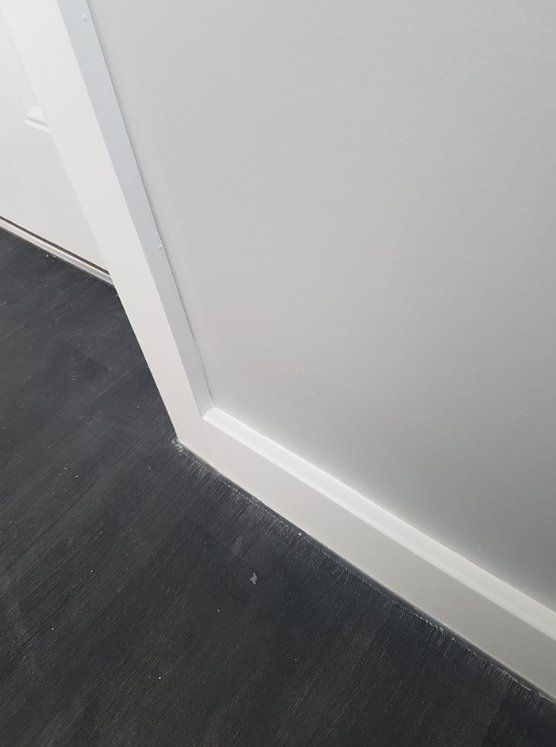 Newly painted light grey wall with white skirting and dark flooring in York