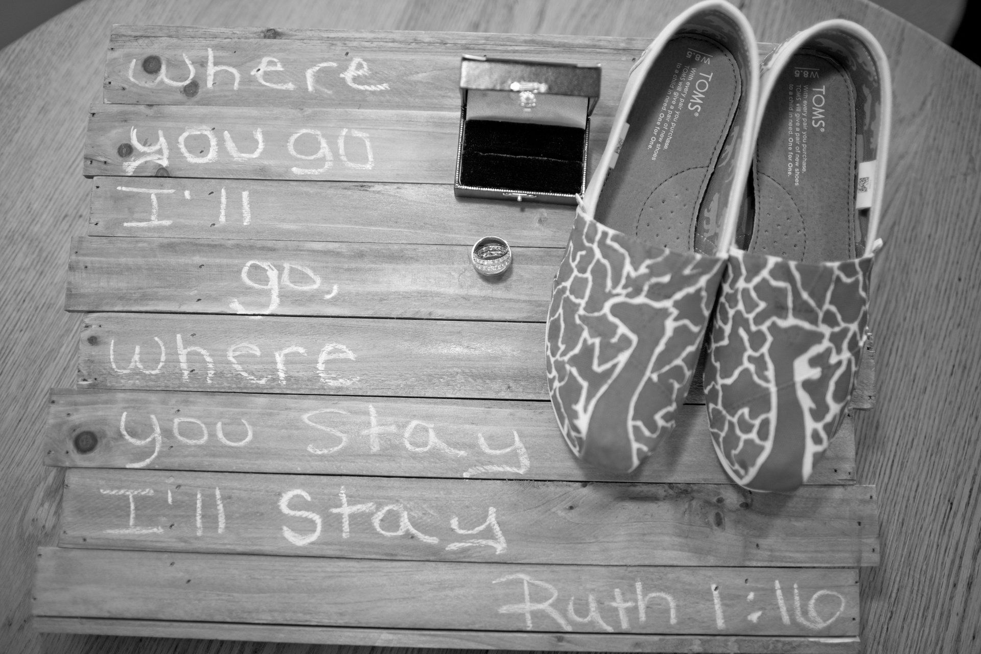 Wedding setup with shoes, rings, and wooden sign with Bible verse 