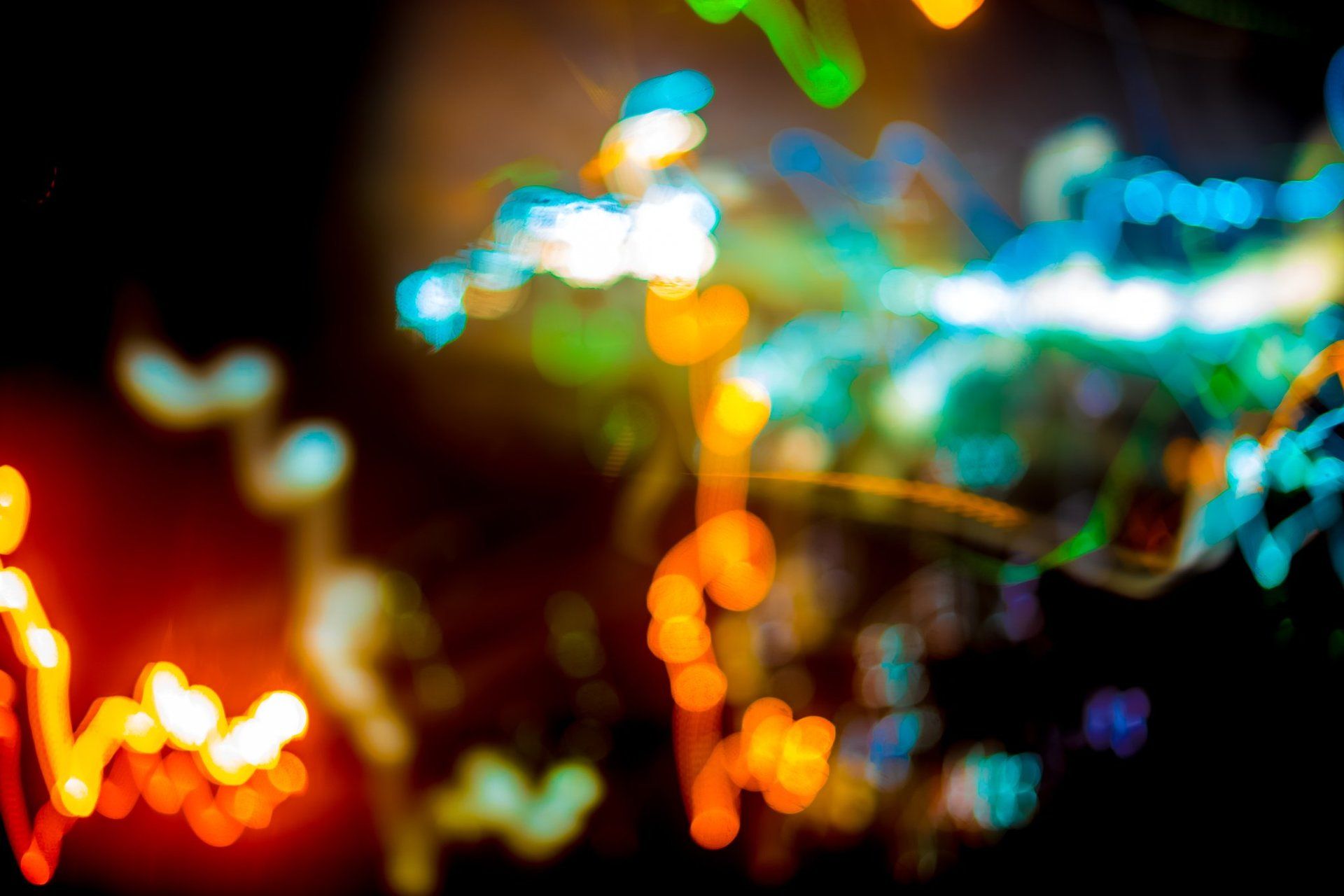 Abstract light streaks in orange, green, and blue against a black background.