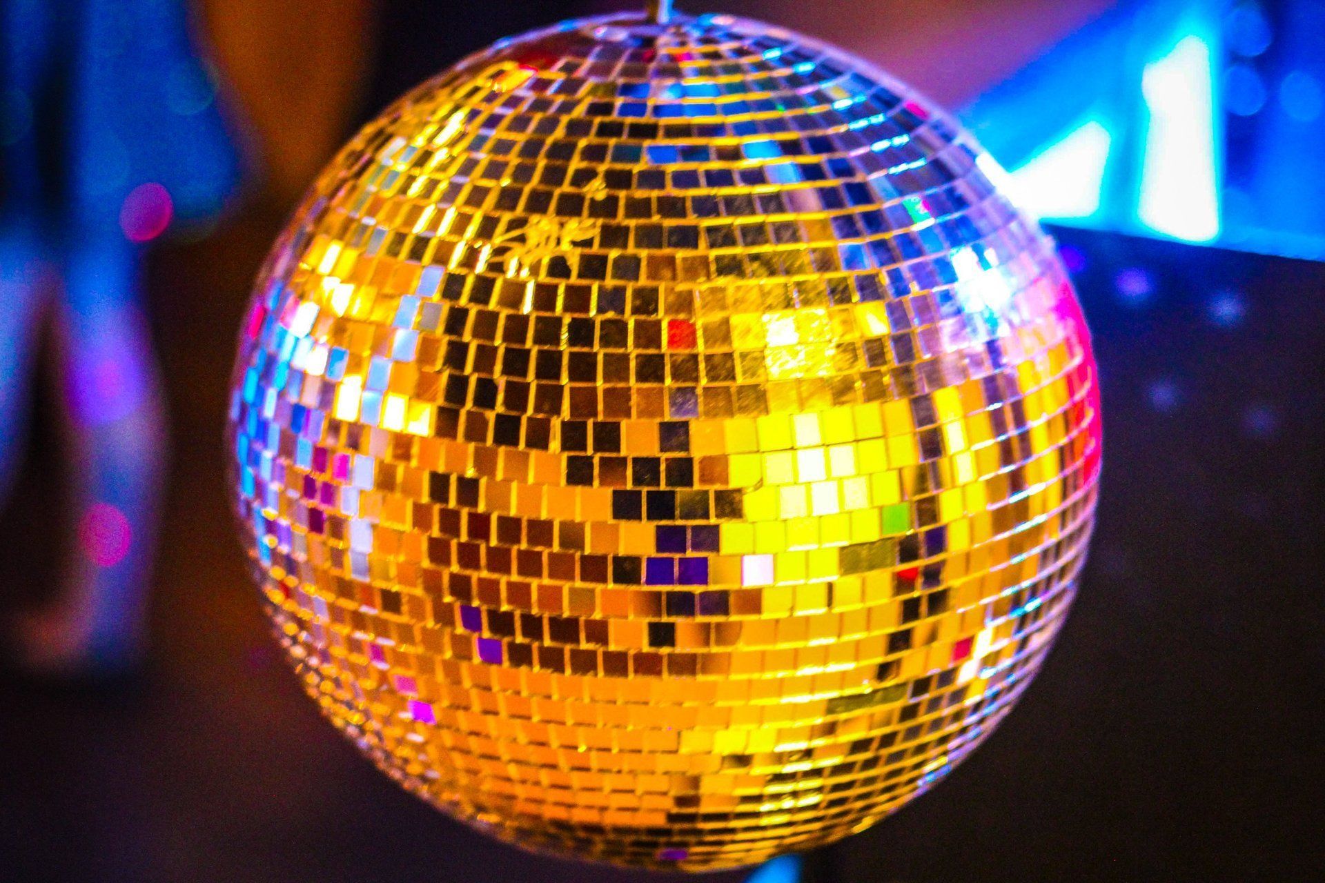 Disco ball hanging, reflecting colorful lights in a dark setting.