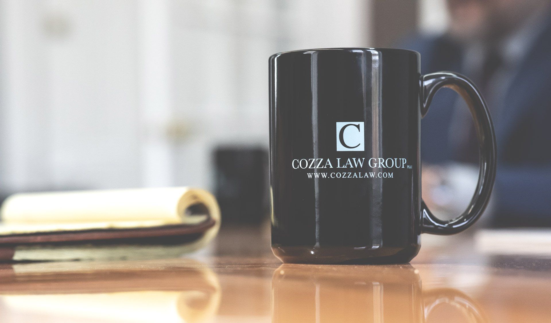 A black coffee mug with the letter c on it is sitting on a wooden table.