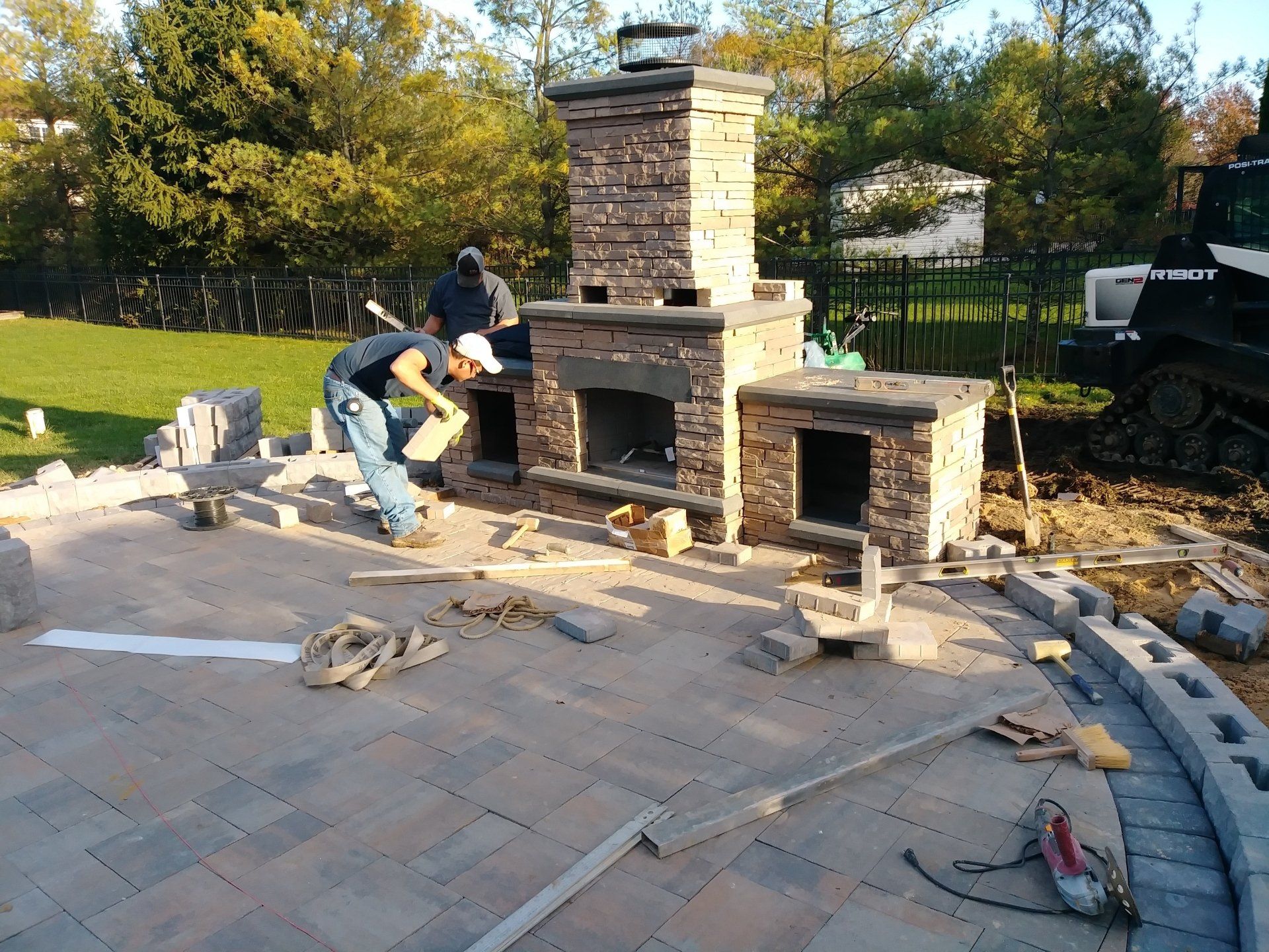 A beautiful small, urban backyard garden featuring a tumbled paver patio, flagstone stepping stones, and a variety of trees, shrubs and perennials add colour and year round interest.