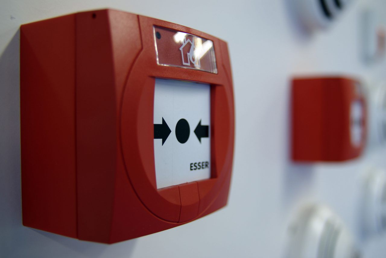 Rode brandmelder op een witte muur met een rood indicatielampje erboven.