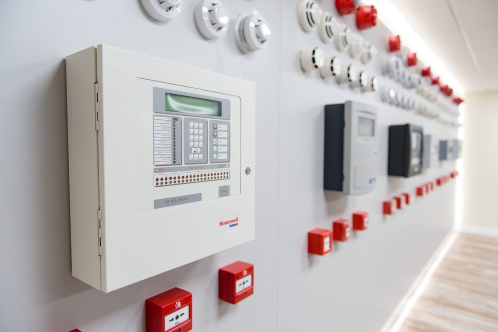 Wandgemonteerde bedieningspanelen en schakelaars in een lichte industriële gang.