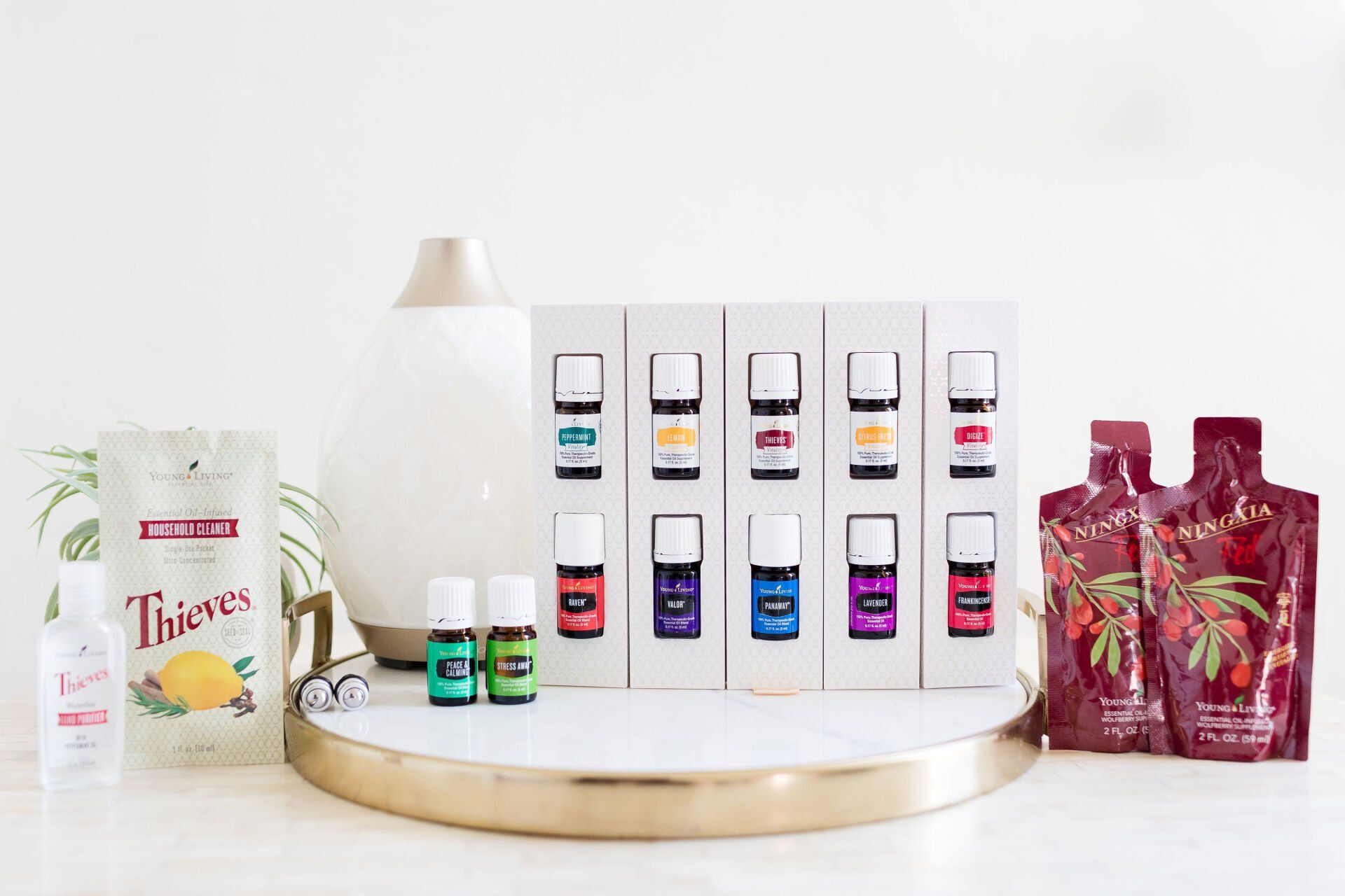 Assorted skincare and beauty products displayed on a white tabletop with gold tray and gift bags