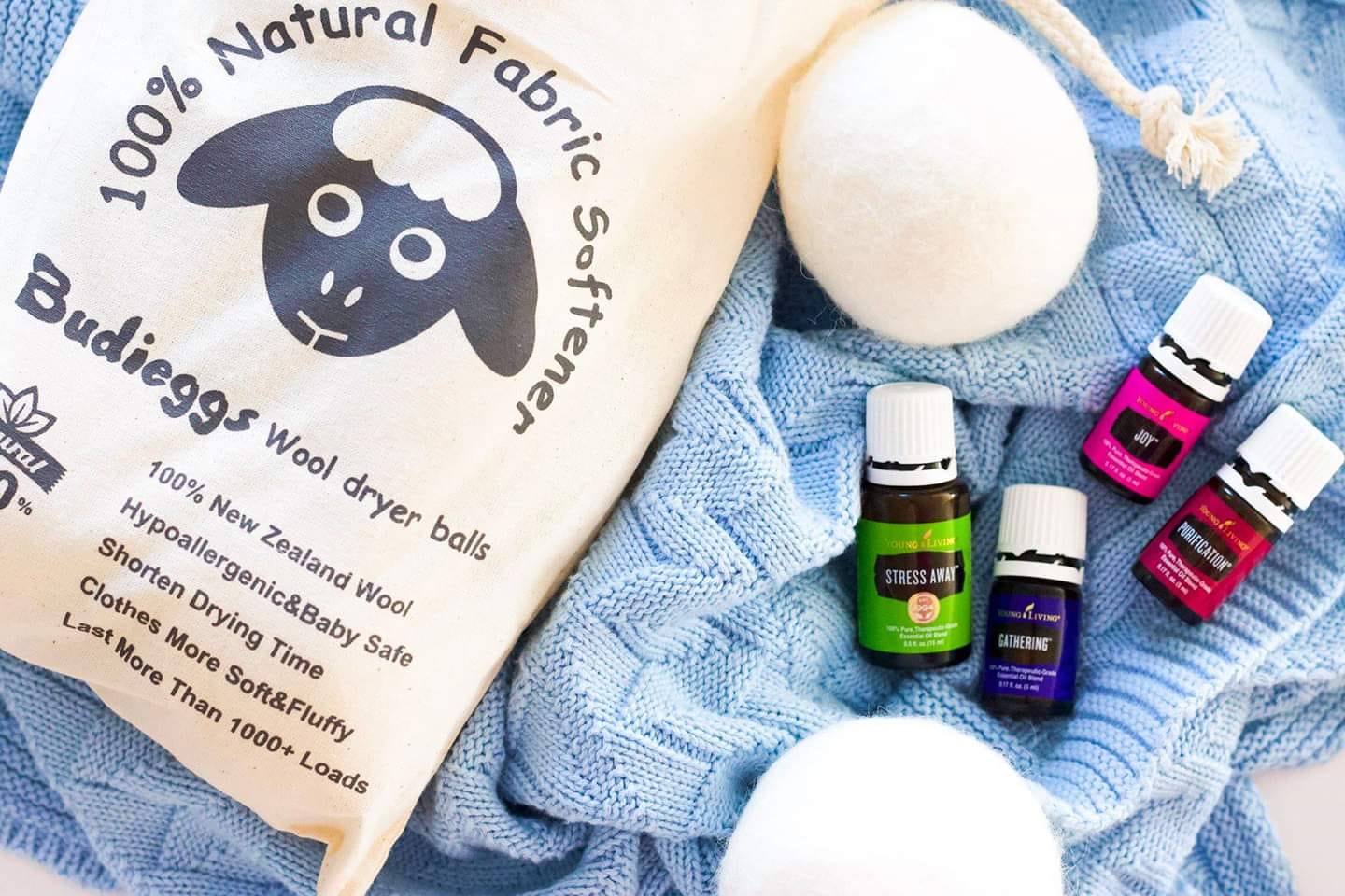 Natural fabric bag, folded blue cloth, cotton balls, and small essential oil bottles on a white background