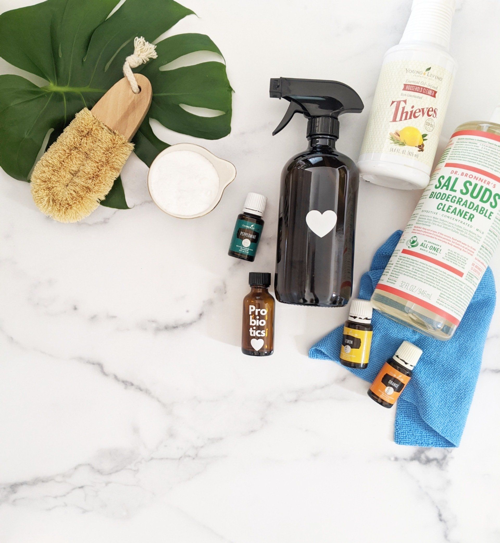 Cleaning supplies and tools on a white marble surface, including spray bottles, brushes, and microfiber cloths.