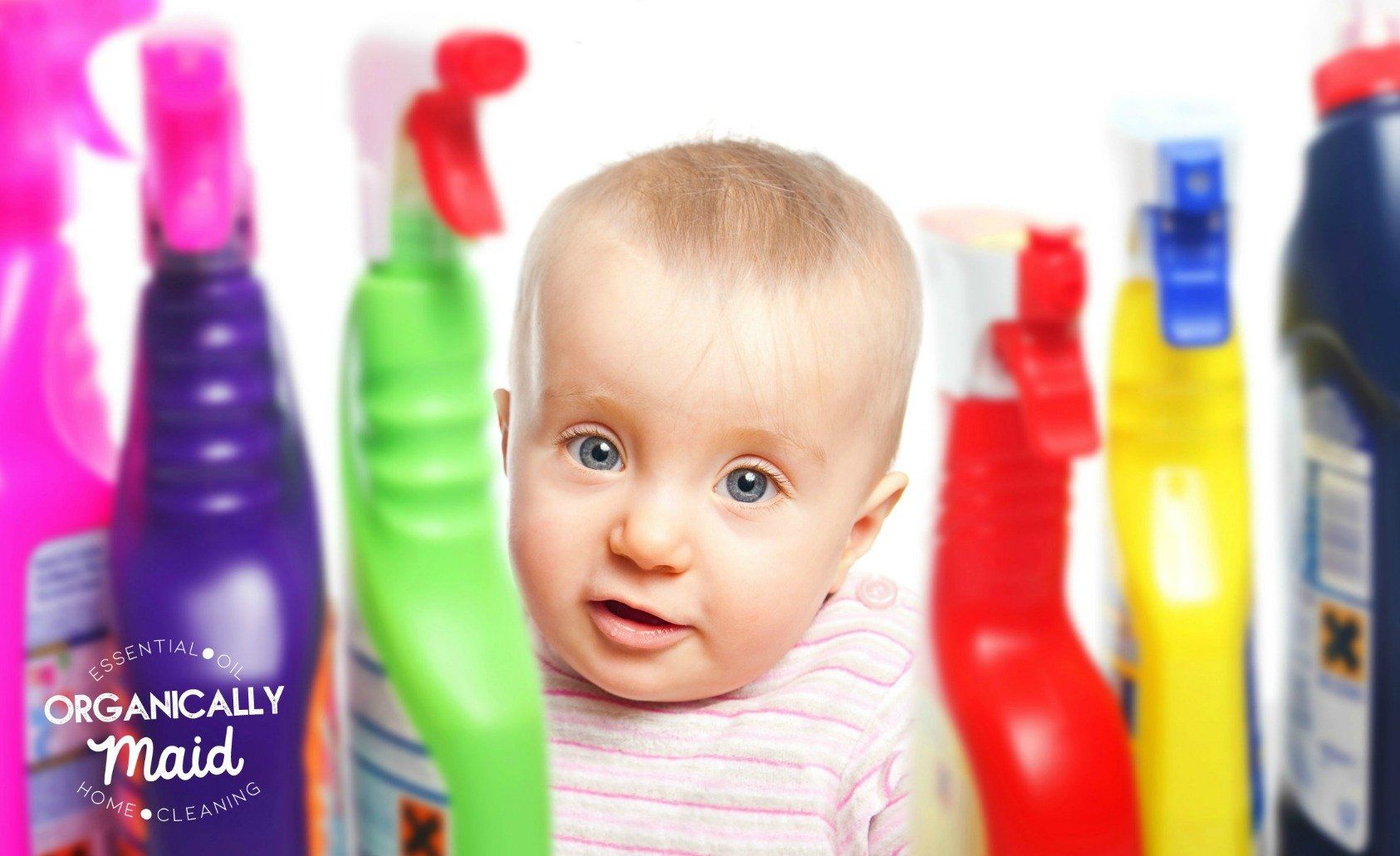 Baby peering between colorful bottles on a bathroom shelf, looking curious at the camera
