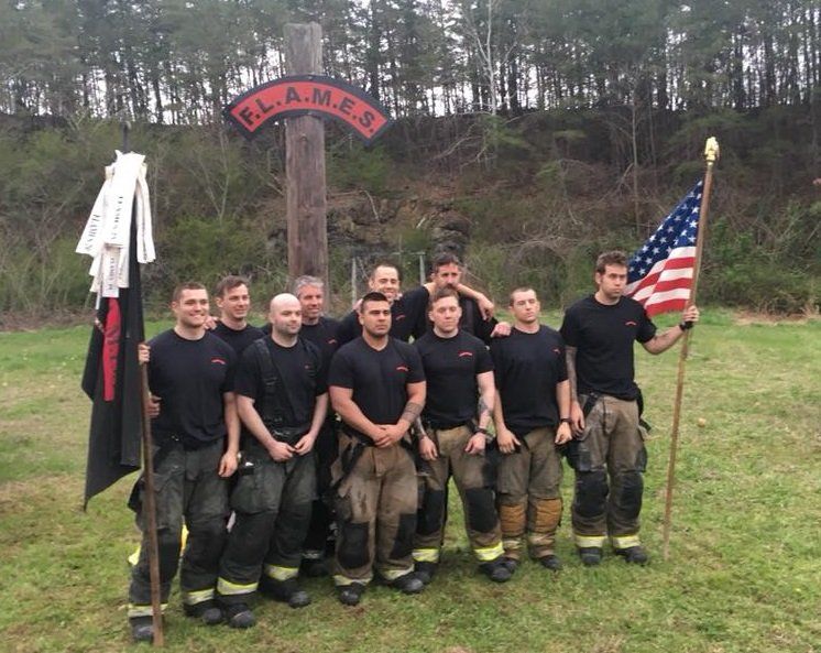 A group of firefighters standing in front of a sign that says flames
