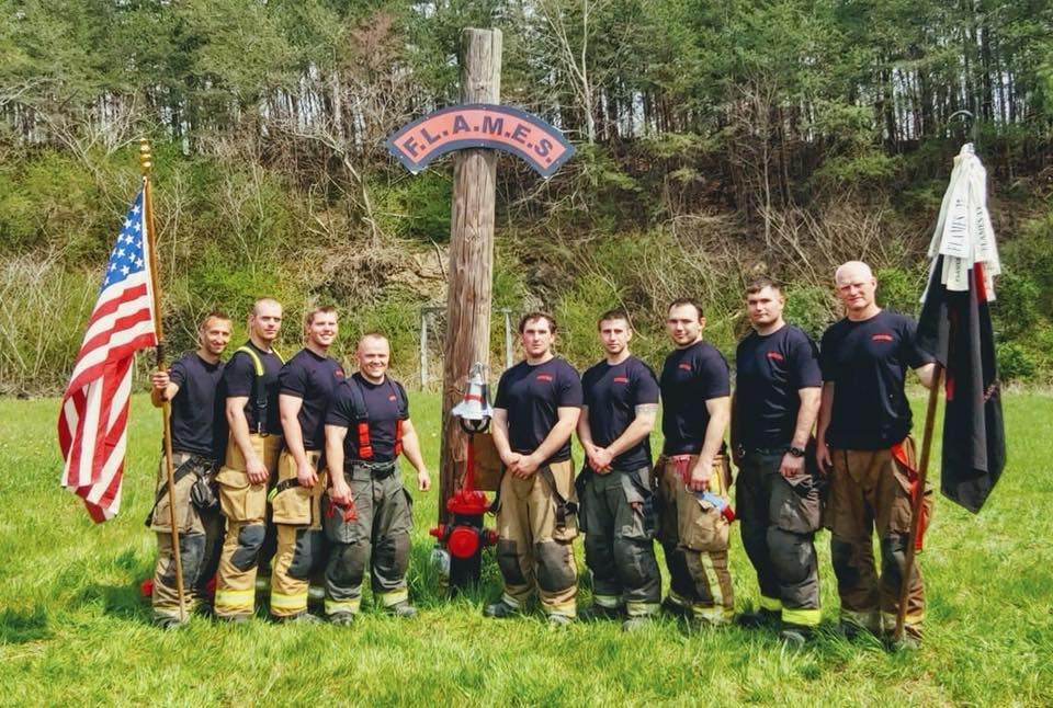 A group of firefighters are posing for a picture in a field.