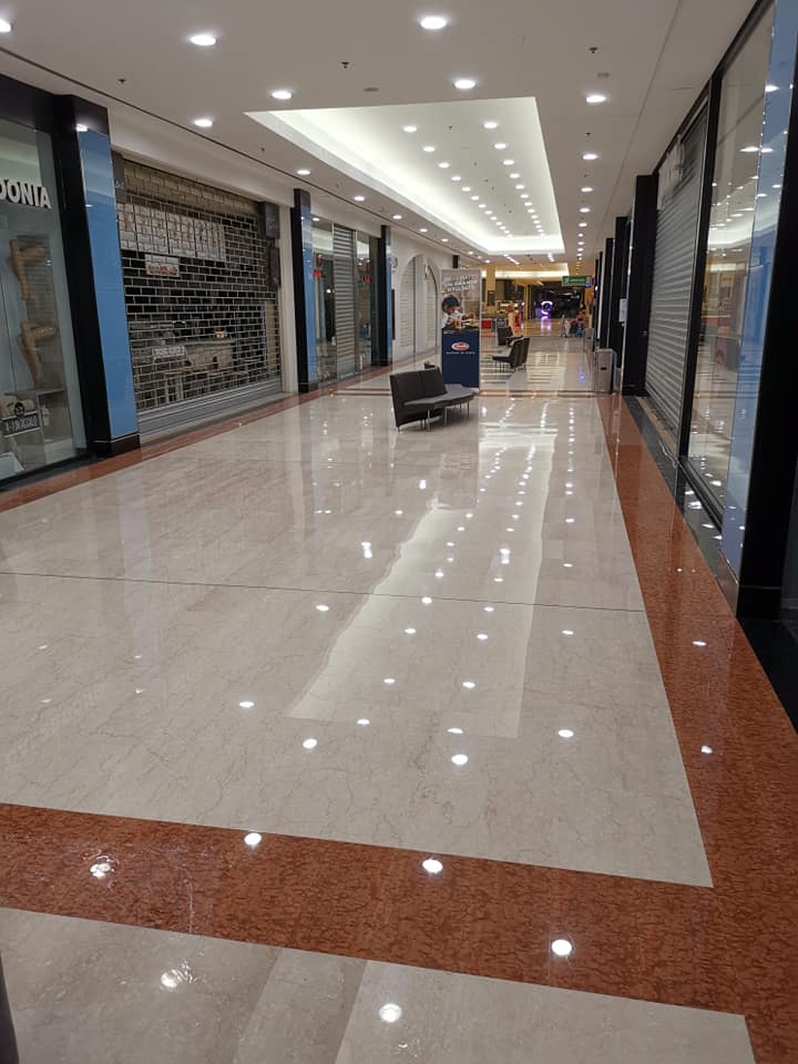 Empty mall hallway with closed storefronts, polished floor reflecting lights.
