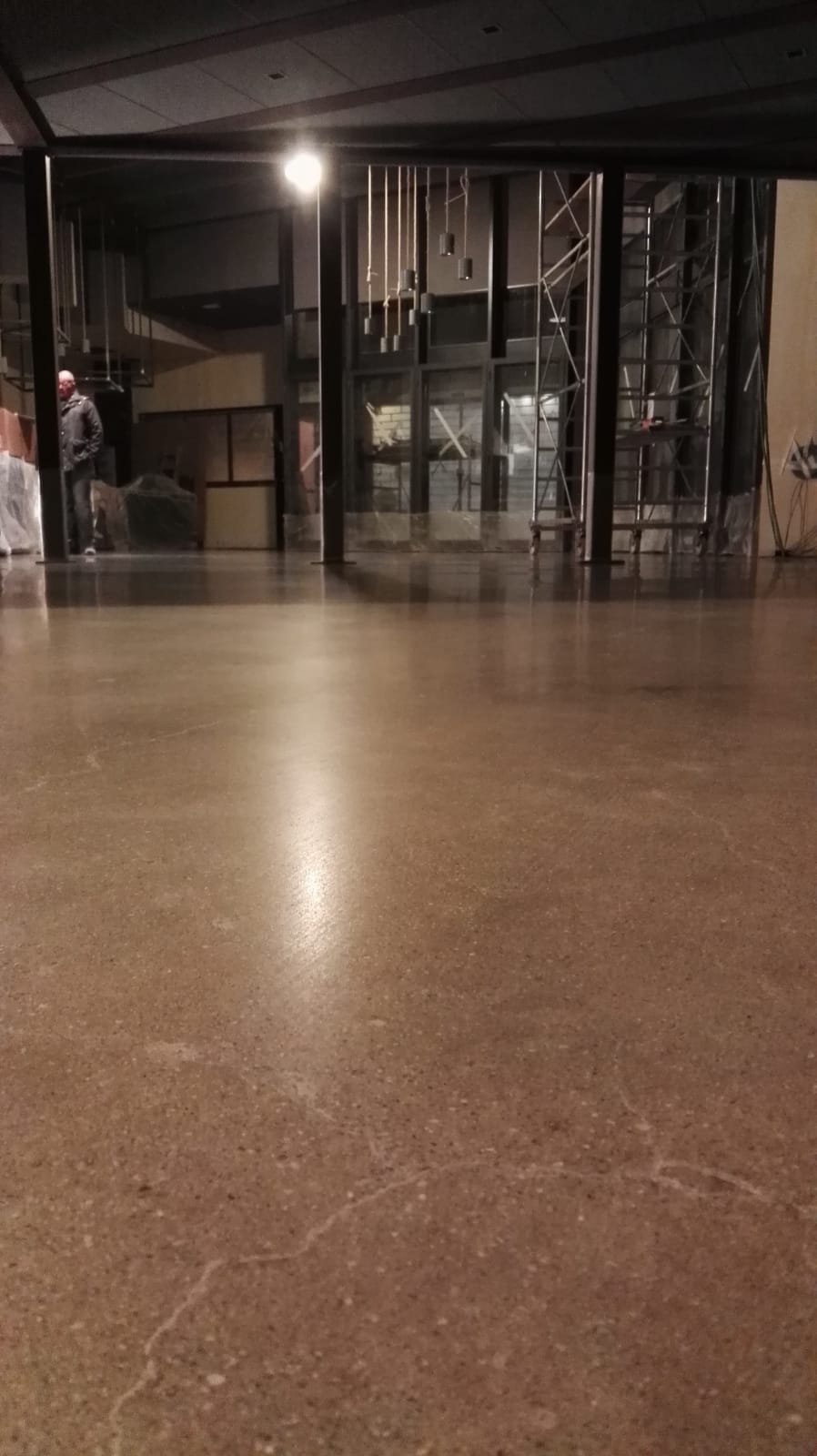 Polished brown concrete floor reflecting overhead light, with a partially visible entryway.