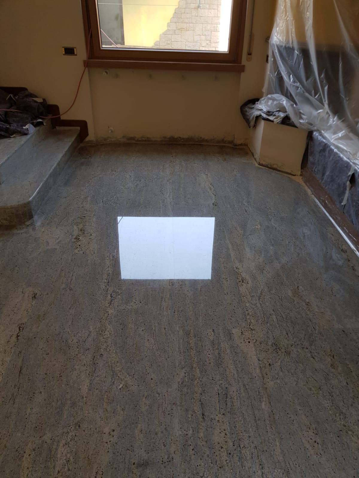 Polished gray granite floor reflecting light from a window.