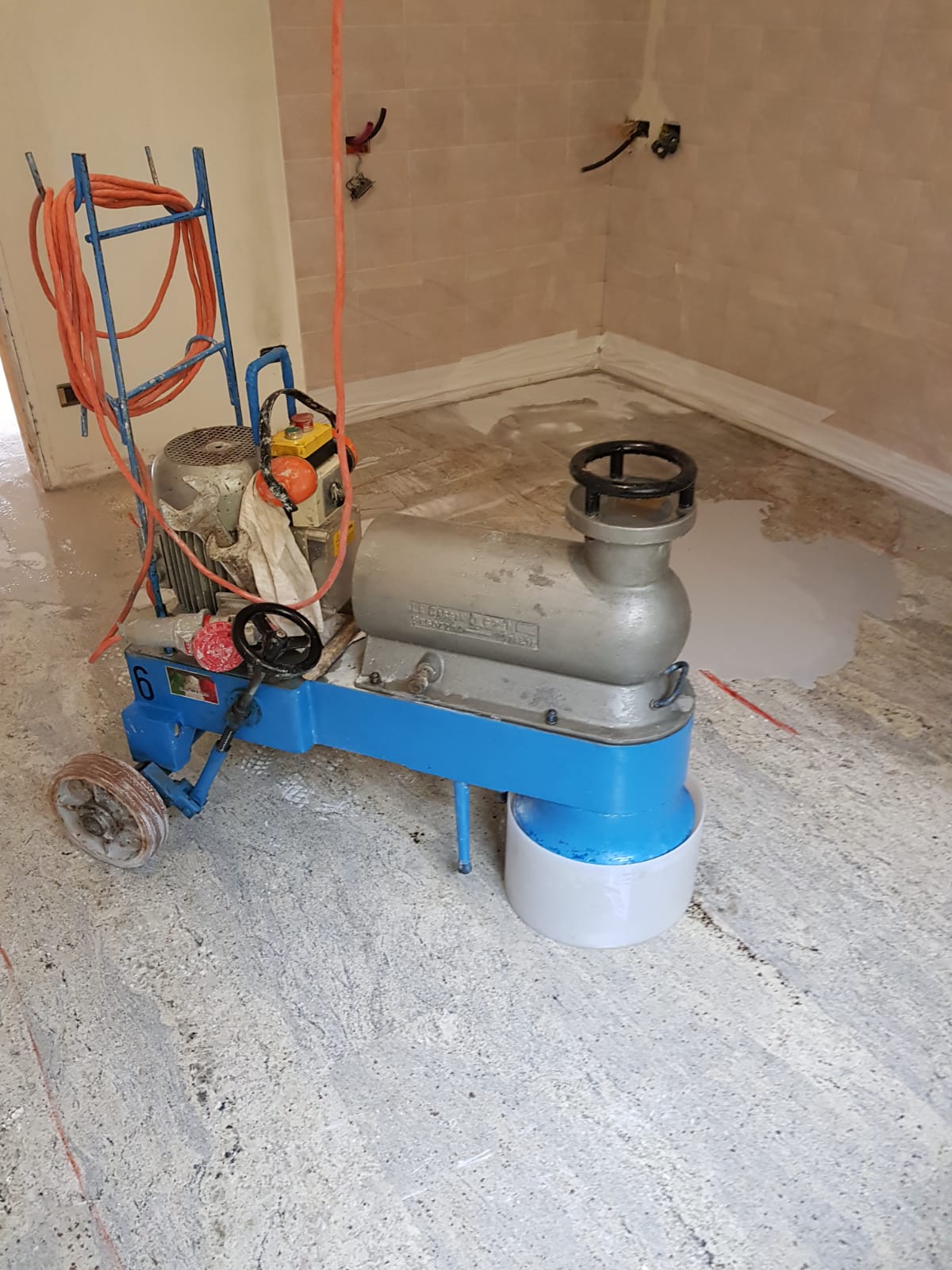 Floor grinding machine in a room with light-colored walls, grinding a cement floor.