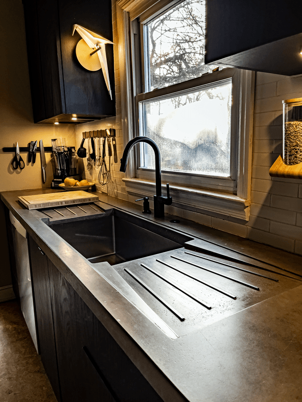 a concrete kitchen countertop with dual drainboards and sliding cutting board.
