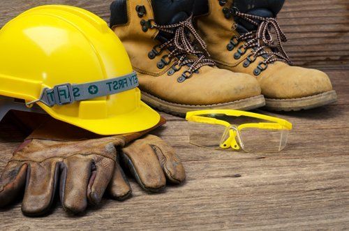 guanti, casco, occhiali e scarpe antinfortunistica su tavola di legno