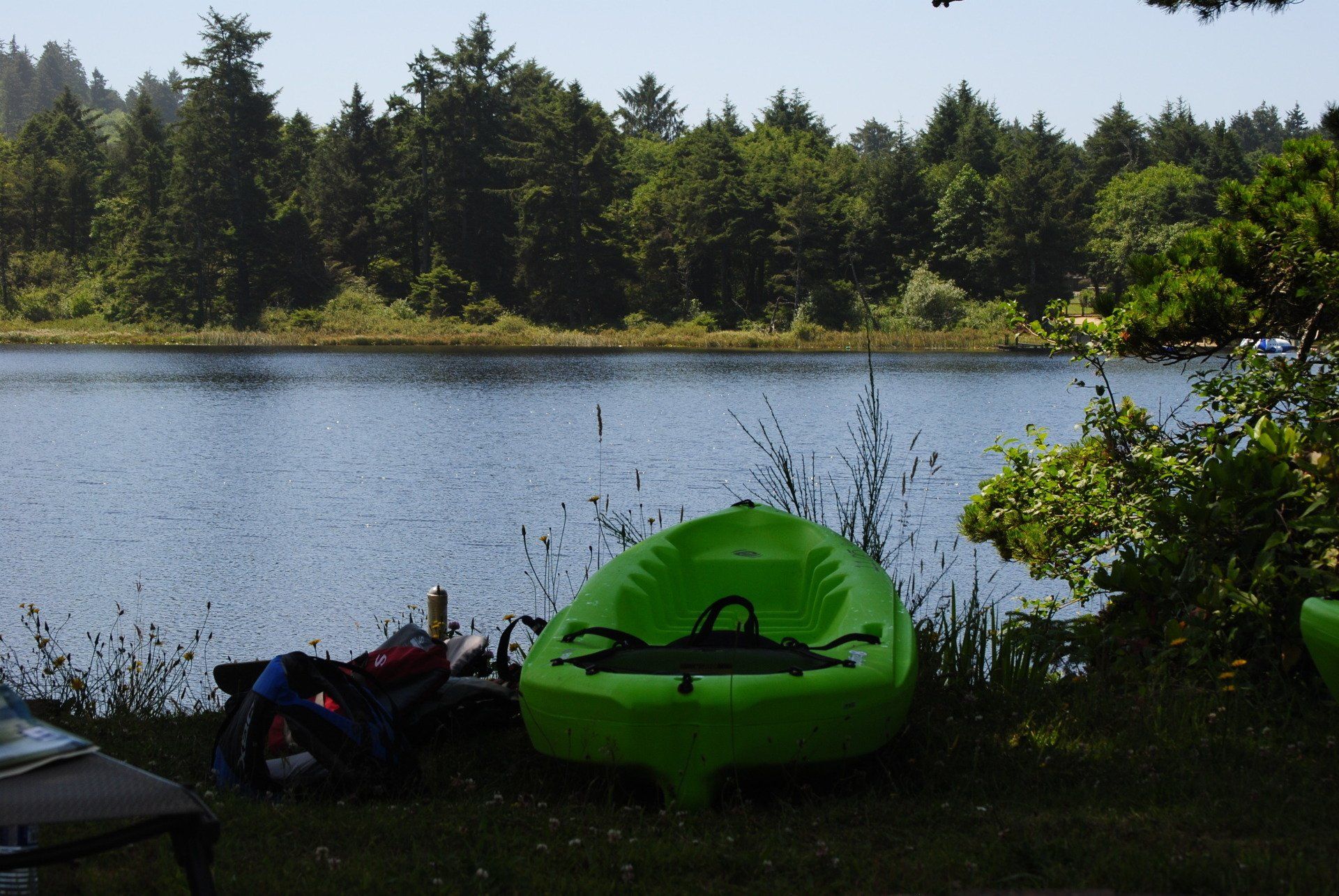 A green kayak sits on the shore of a lake