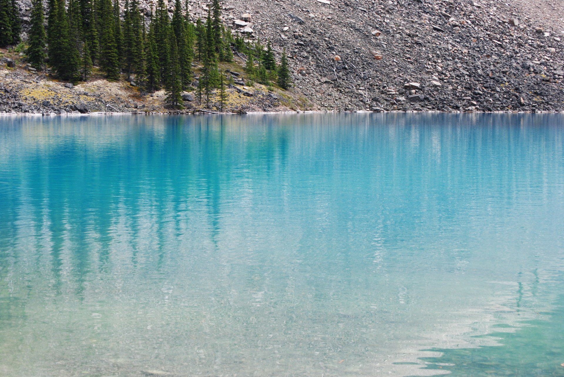 A blue lake surrounded by rocks and trees with a mountain in the background.